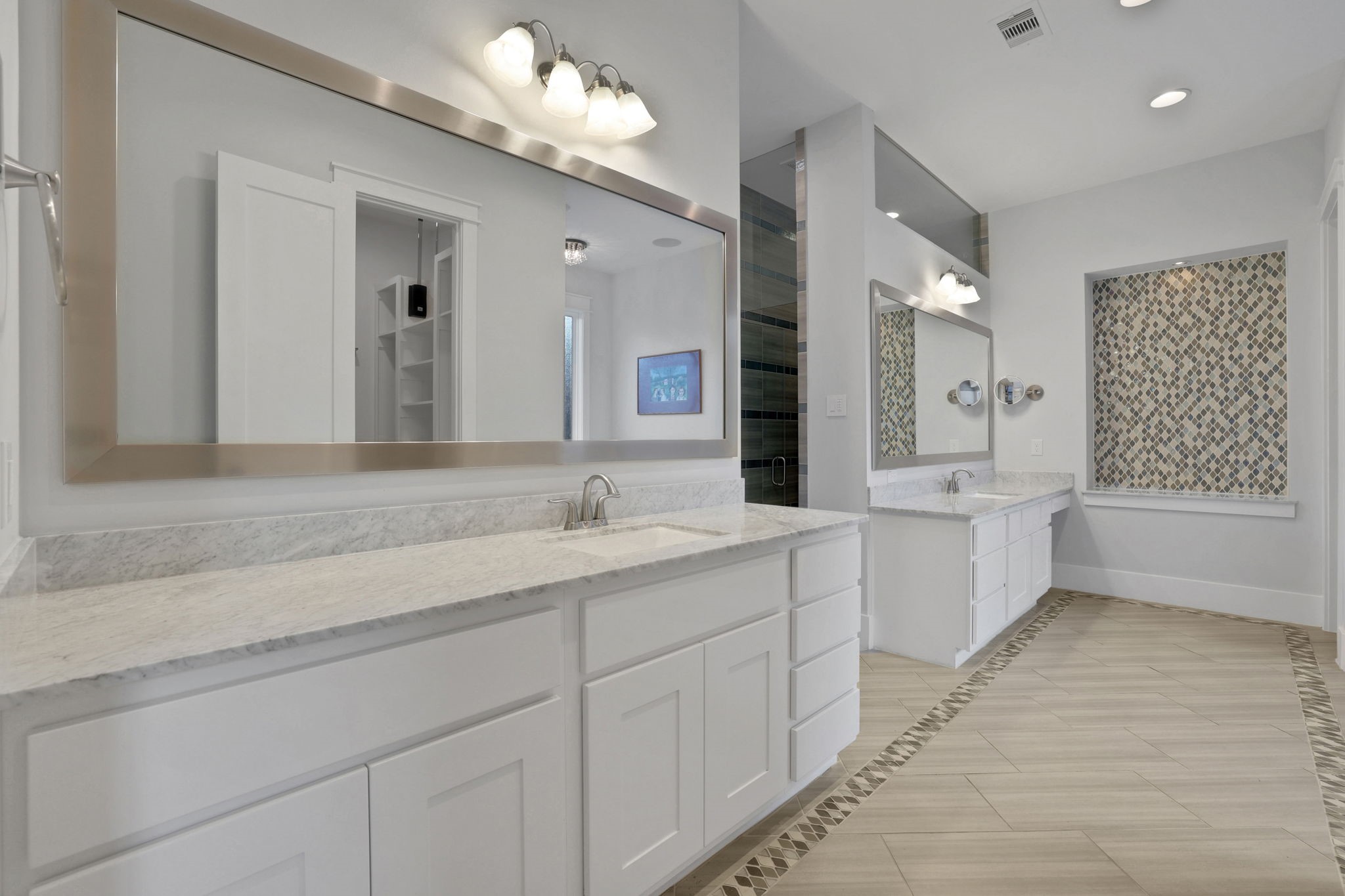 A long vanity and expansive mirror anchor the bath.