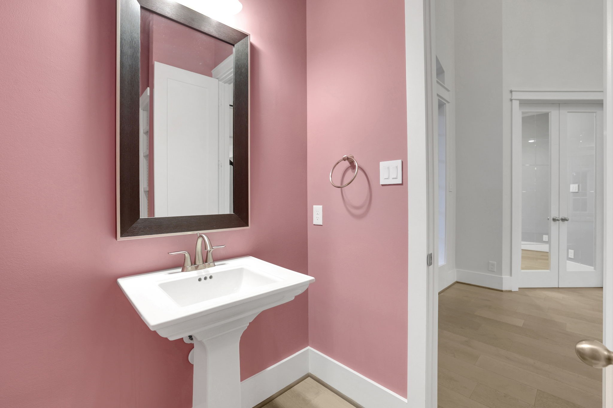 A pedestal sink and framed mirror give the powder bath a bold look.