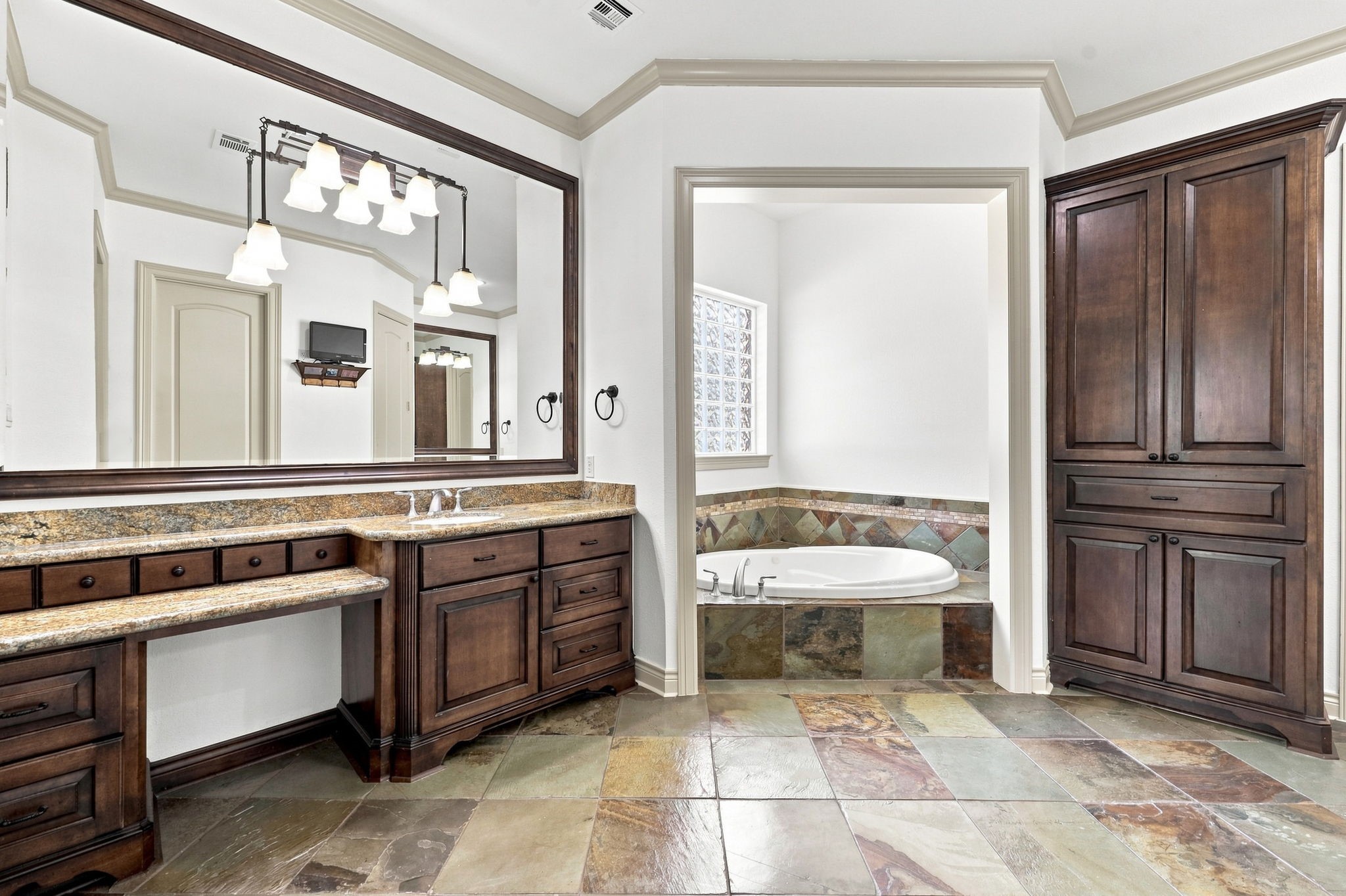The luxurious Primary Bathroom offers custom cabinetry, gorgeous slate flooring, and elegant double vanities, creating a sophisticated and relaxing retreat.