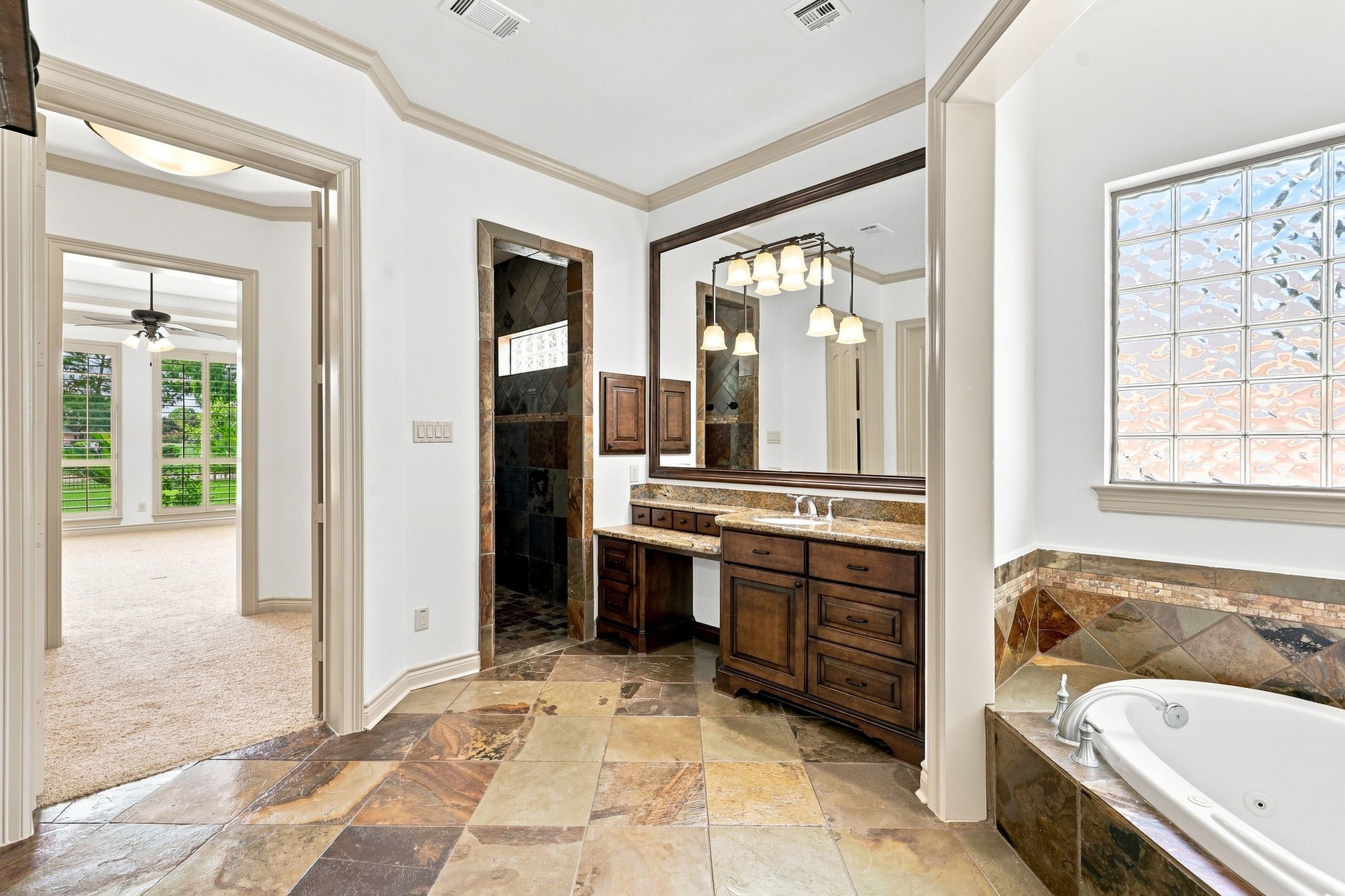 This view showcases the entrance to the spacious walk-in shower, beautifully finished with floor-to-ceiling slate tile. Looking back toward the Primary Bedroom, the view highlights the seamless flow between the luxurious bath and private bedroom retreat.