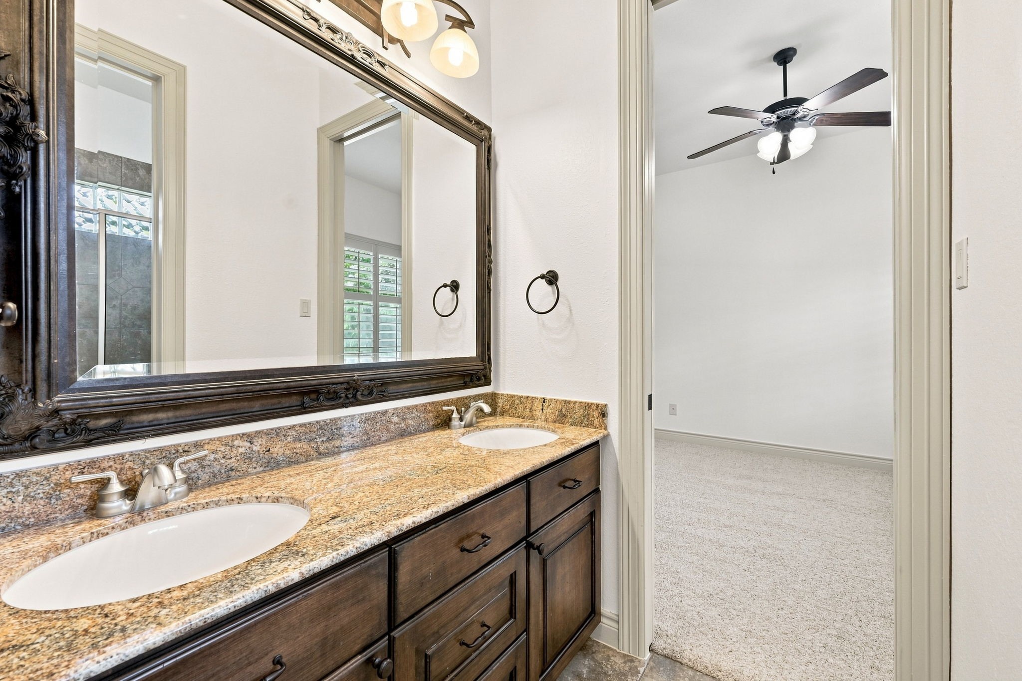 This beautifully appointed Full Bath serves two of the secondary bedrooms and features dual sinks, custom cabinetry, and an elegant framed mirror. Oil-rubbed bronze light fixtures add a sophisticated finishing touch to this stylish and functional bathroom.