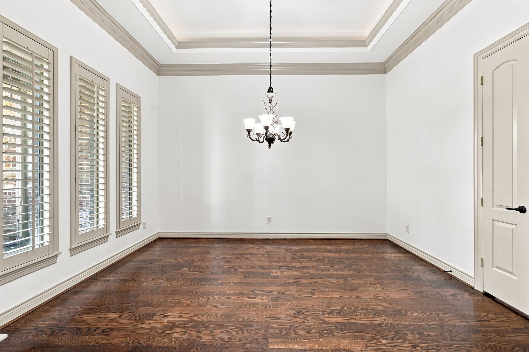 The elegant Formal Dining room is perfectly suited for holiday celebrations and memorable family gatherings. A beautiful designer paint color complements the space, while three windows with Plantation Shutters provide an abundance of natural light and timeless appeal. The raised ceiling adds volume and architectural interest, beautifully accented by a sophisticated oil-rubbed bronze chandelier.