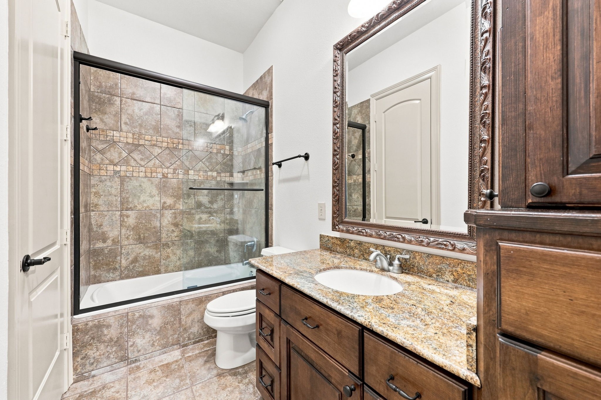 This Full Bath serves the two Secondary Bedrooms featured in the previous 2 photos. The bath offers a tub and shower combination, custom cabinetry, a gorgeous granite countertop, and beautiful tilework, creating a stylish and functional space for family and guests.