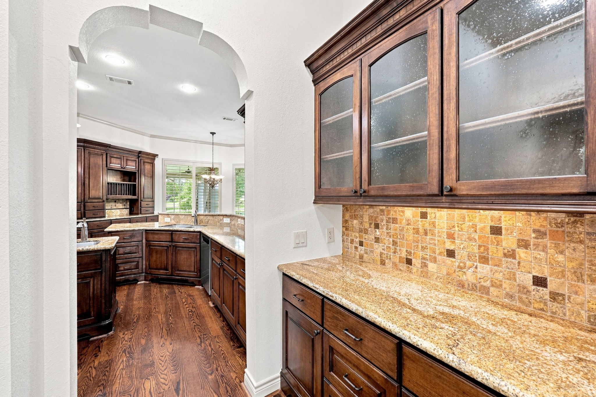 The elegant Butlers Pantry conveniently connects the Formal Dining and Kitchen areas, making entertaining effortless. Beautiful glass-front cabinetry provides a stylish way to display favorite dishes and serving pieces, while gorgeous granite countertops and abundant storage offer plenty of space for dinnerware, glassware, and entertaining essentials.