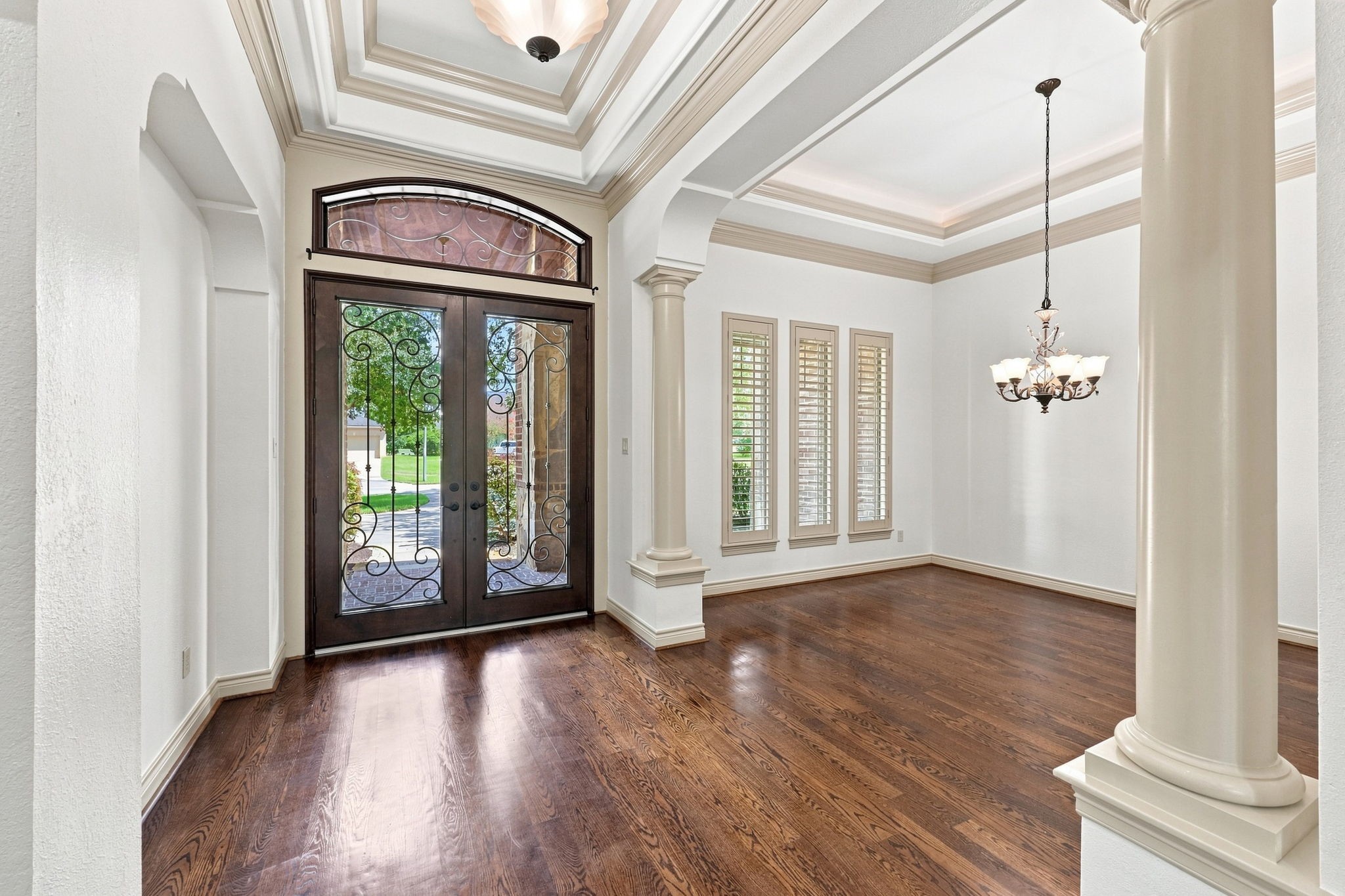 Looking back toward the front entrance, this view showcases the impressive double iron doors, accented by an elegant transom window above that allows an abundance of natural light to fill the foyer. The striking doors and light-filled entry create a beautiful first impression and complement the homes sophisticated architectural details.