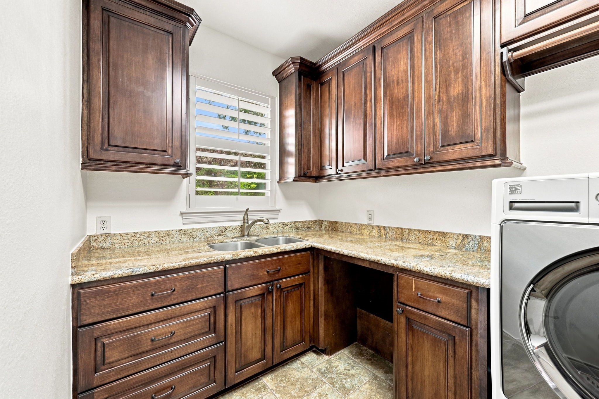 The oversized Laundry Room is both beautiful and highly functional, featuring lots of custom cabinetry, gorgeous granite countertops with generous space for folding clothes, and a convenient stainless-steel sink. Thoughtfully designed for everyday efficiency, this spacious laundry room offers exceptional storage and workspace.