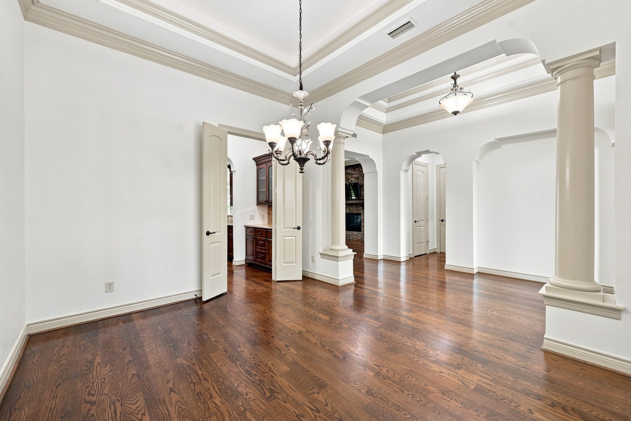 This view from the opposite side of the Formal Dining room highlights the elegant double-door entry leading to the Kitchen and Butlers Pantry. The thoughtfully designed layout creates a seamless flow between the formal dining space and the heart of the home, making entertaining and serving guests effortless.