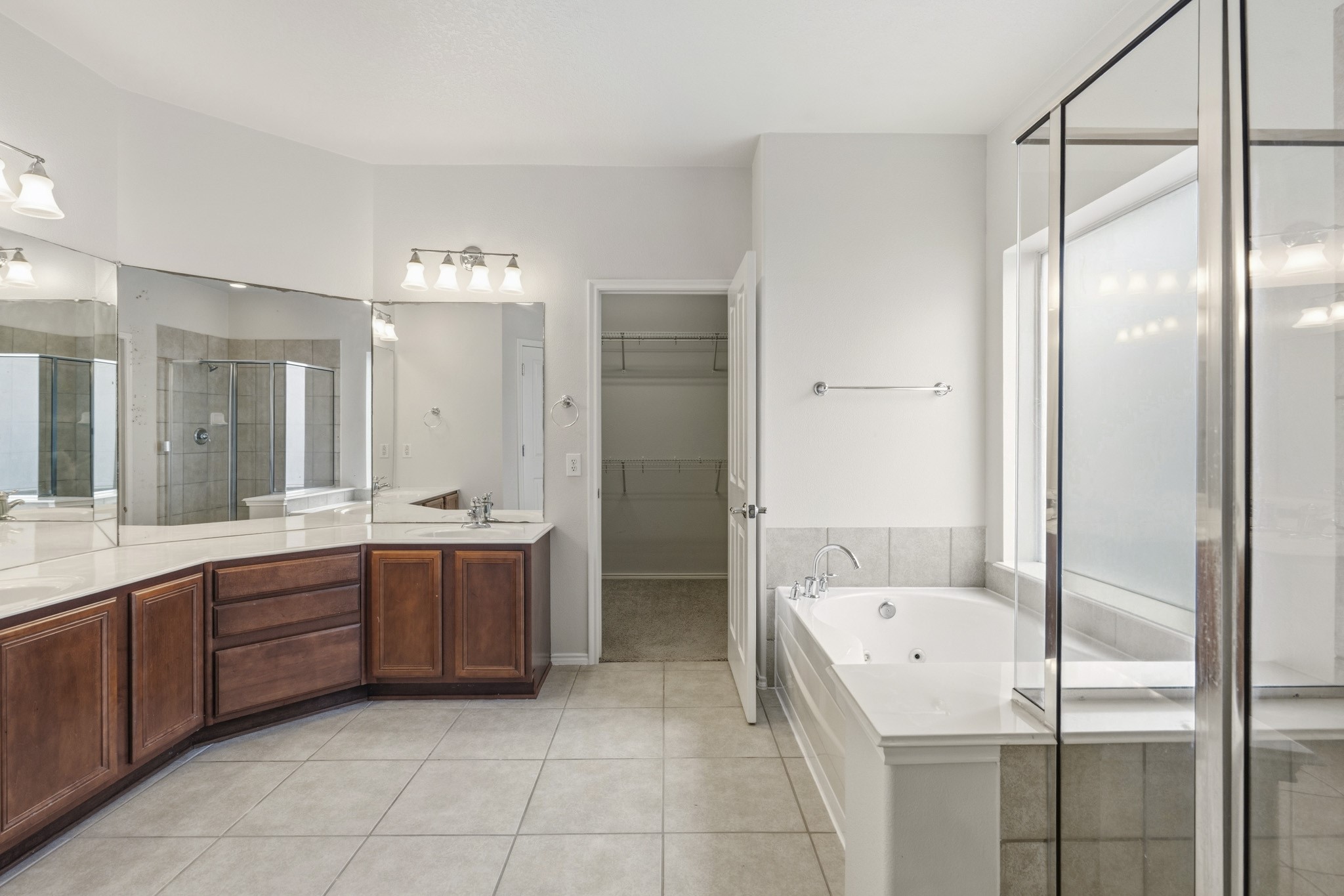 Luxurious primary bath featuring a large walk-in shower, oversized jetted soaking tub, dual vanities with abundant counter space, and an expansive walk-in closet.