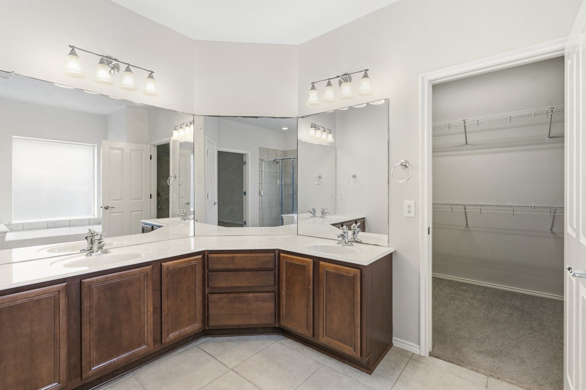 Additional view of the primary bath showcasing extensive storage, dual vanity space, and convenient access to the oversized walk-in closet.