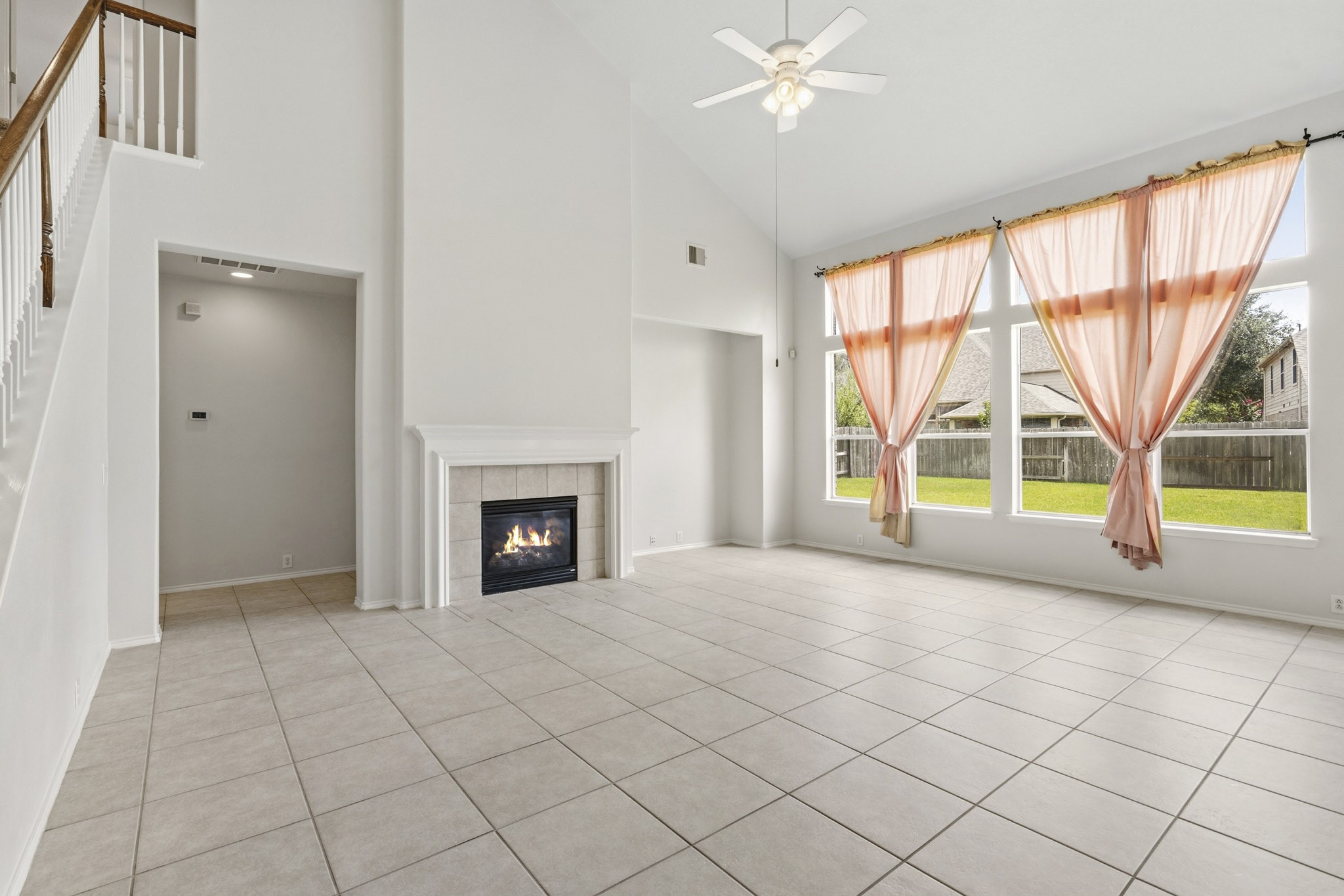 Expansive family room featuring a cozy fireplace, dedicated entertainment space, and views of the oversized, pool-sized backyard.