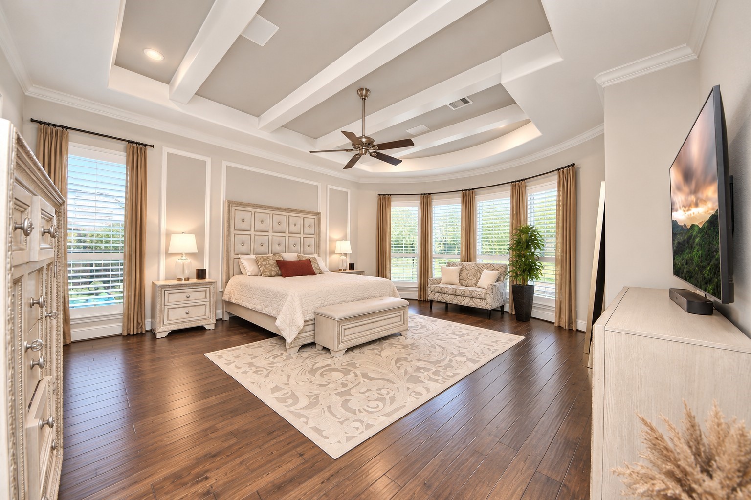 Expansive 19' x 20' primary suite featuring a tray-style ceiling accented with decorative beams, elegant bay windows, Plantation shutters and built-in surround sound speakers.