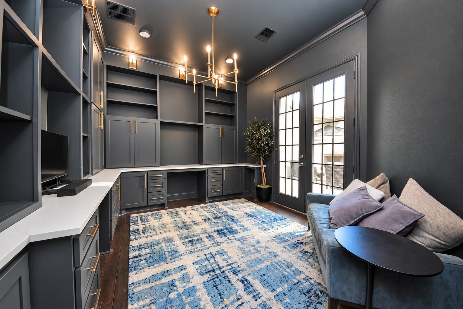 Sophisticated private study featuring rich, dark finishes, custom built-in cabinetry with soft-close drawers, two dedicated workstations, an elegant chandelier, and double doors opening to the private courtyard.