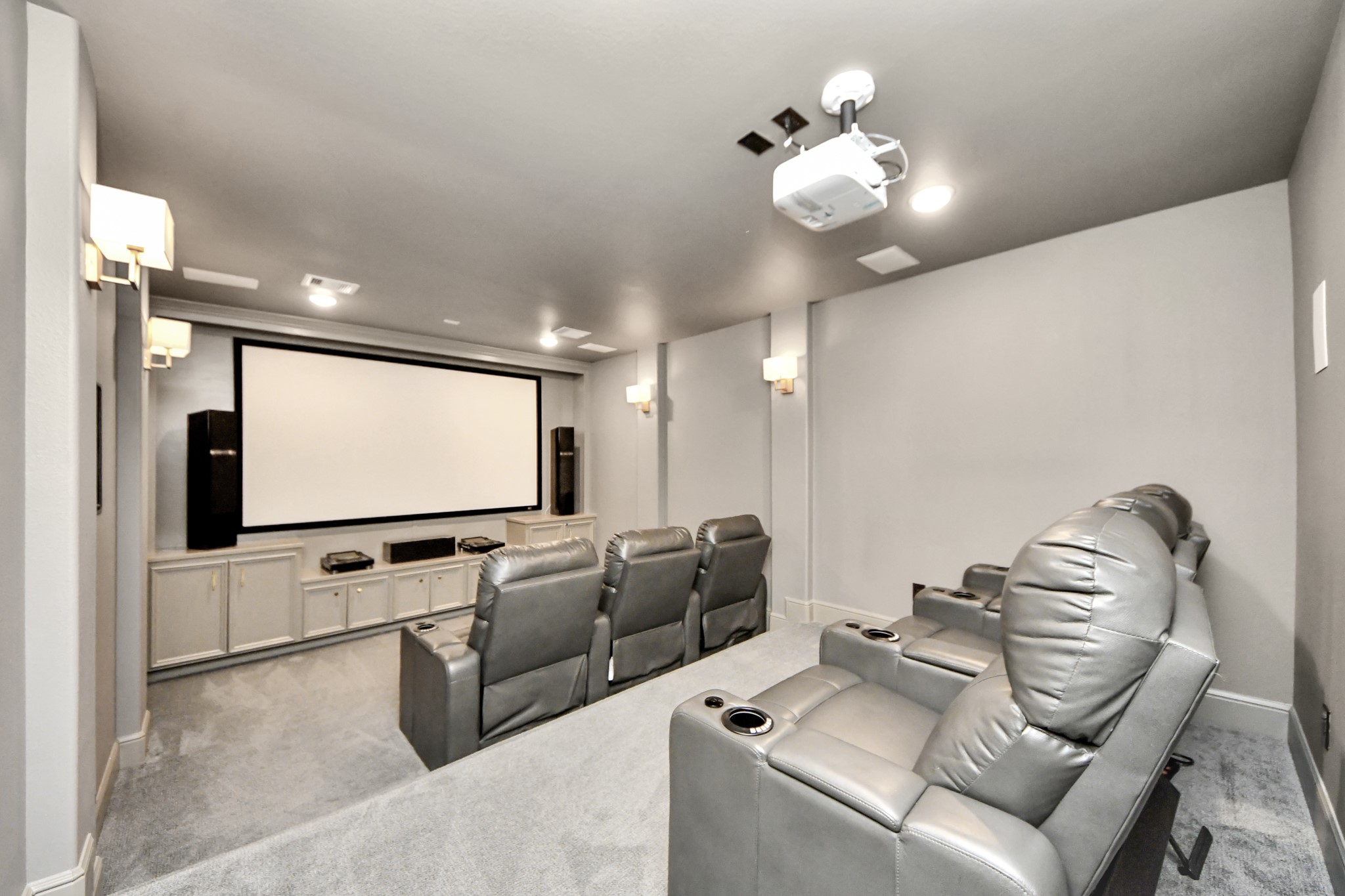 Another view of the private media room showcasing tiered theater seating, a large projection screen, dimmable lighting, and an immersive surround sound system. Premium audio/video equipment and reclining theater seating available with an acceptable full-price offer.
