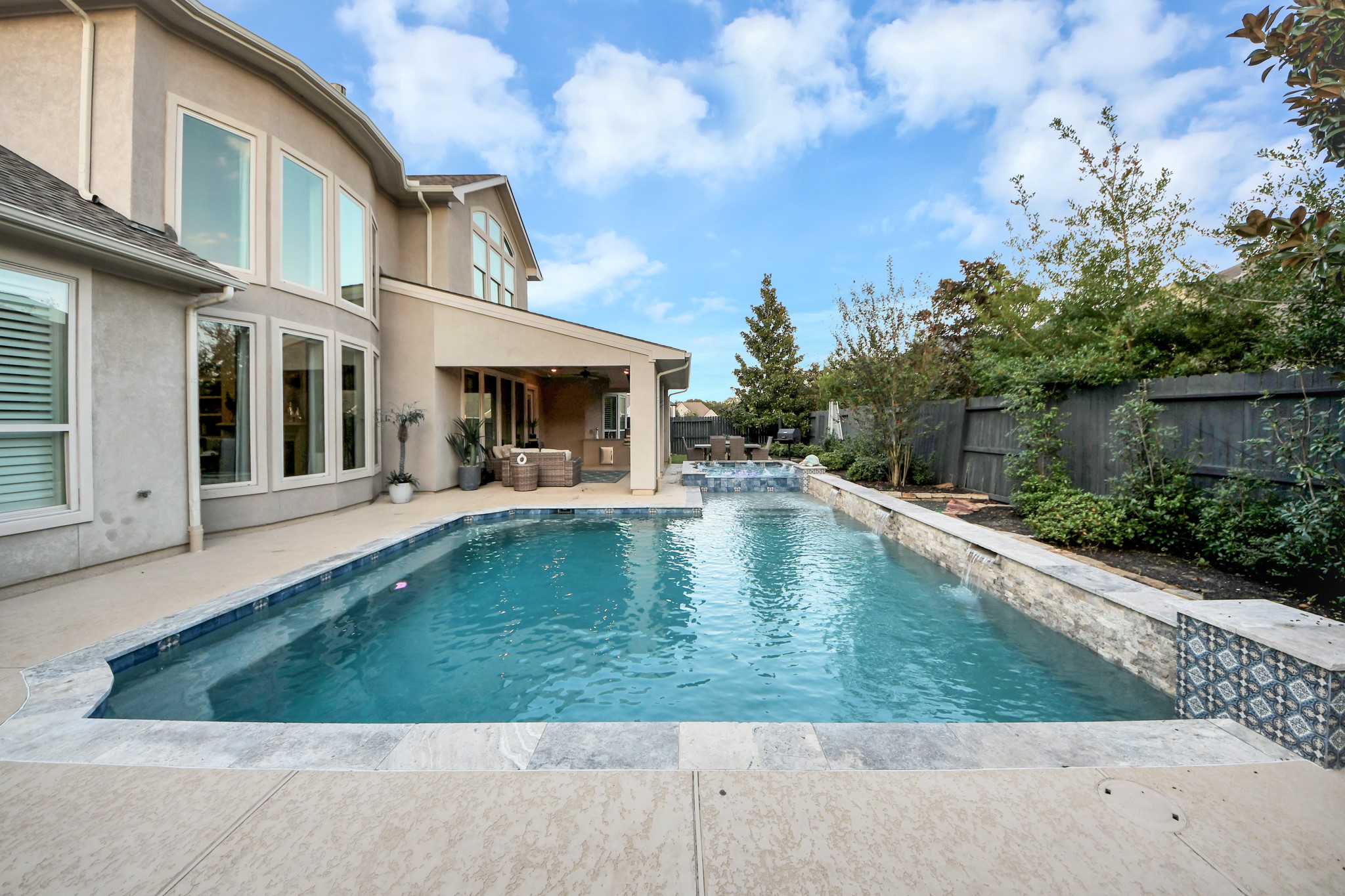Stunning oversized pool built in 2022, featuring three cascading waterfalls, a tanning ledge for in-water lounging, and built-in bench seating along the pool's perimeter. Designed for relaxation and entertaining, with a spacious spa and exceptional backyard privacy.
