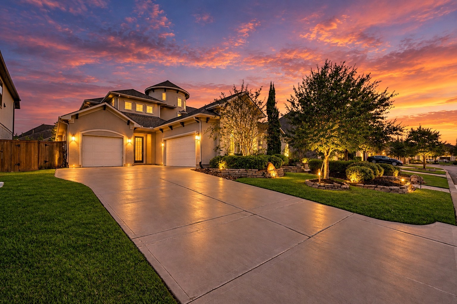 Three-car garage with a dedicated single-bay garage equipped with a mini-split HVAC system, complemented by an expansive driveway and beautifully illuminated landscaping.