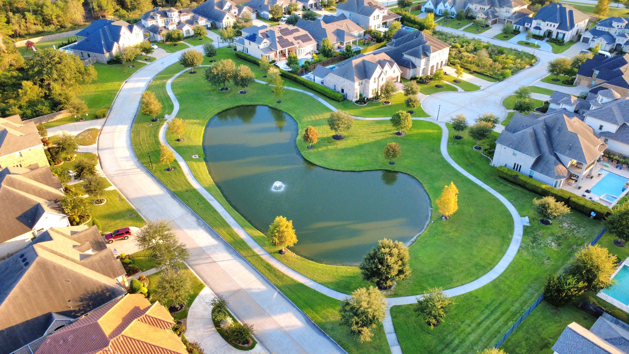 Beautiful aerial view of the gated Bridlecreek community, showcasing its scenic lake, lush green spaces, and walking trails surrounded by beautifully maintained homes and landscaping.