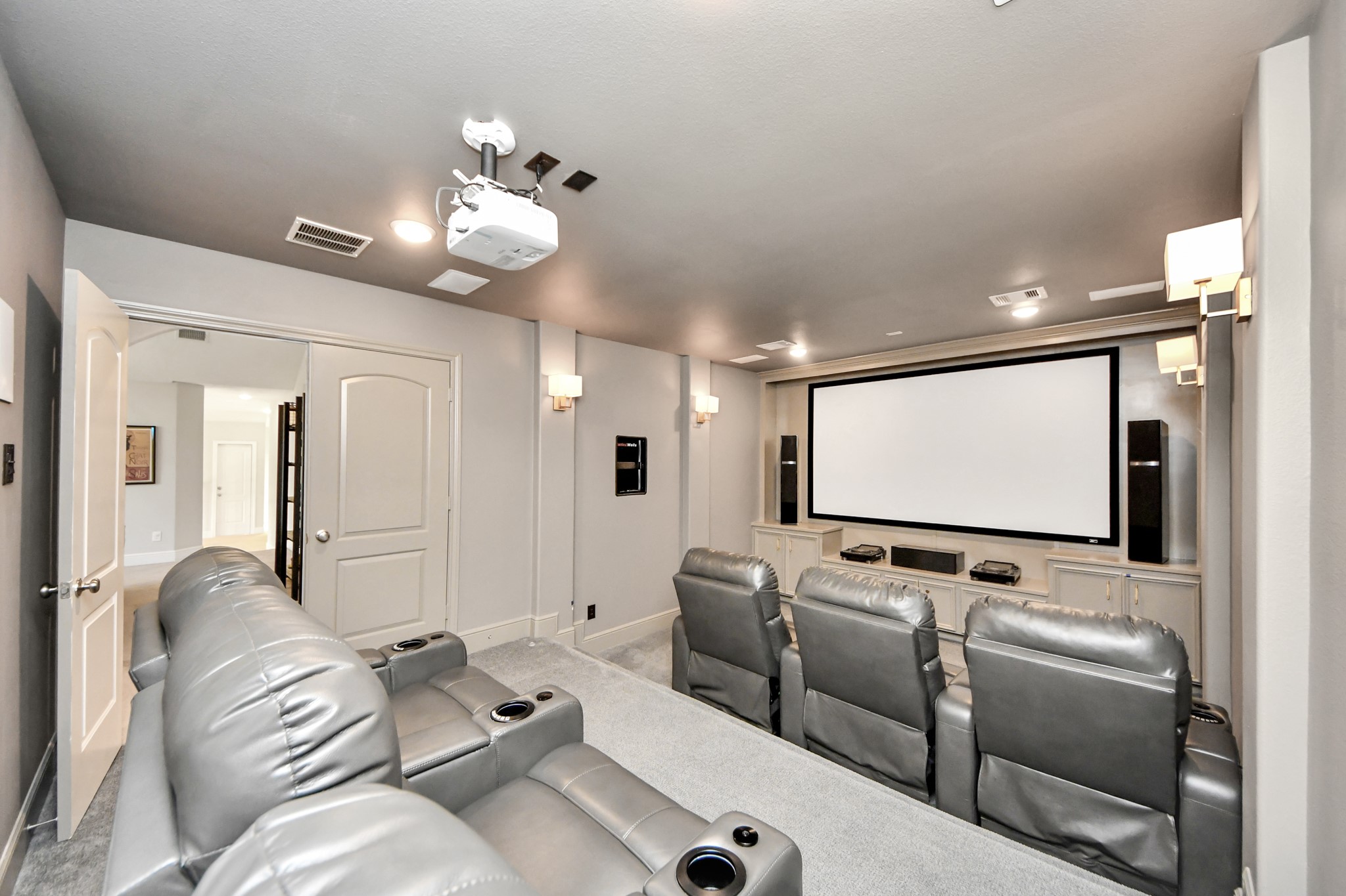 Private theater-style media room featuring tiered flooring for reclining theater seating, dimmable lighting, eight built-in surround sound speakers, and a premium projection system. Theater seating and select audio/video equipment available with a full-price offer.