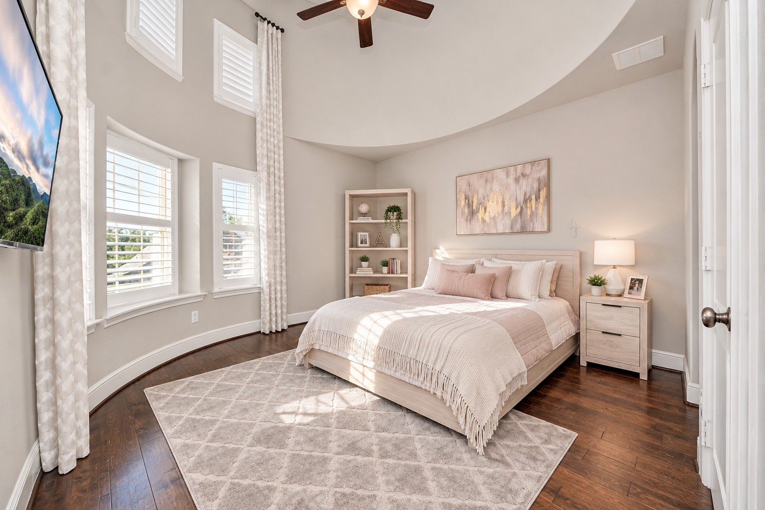 Spacious upstairs secondary bedroom featuring impressive 17-foot ceilings, a curved wall with six windows, plantation shutters, abundant natural light, and direct access to a shared bathroom with its own private vanity area and a shared tub/shower combination.