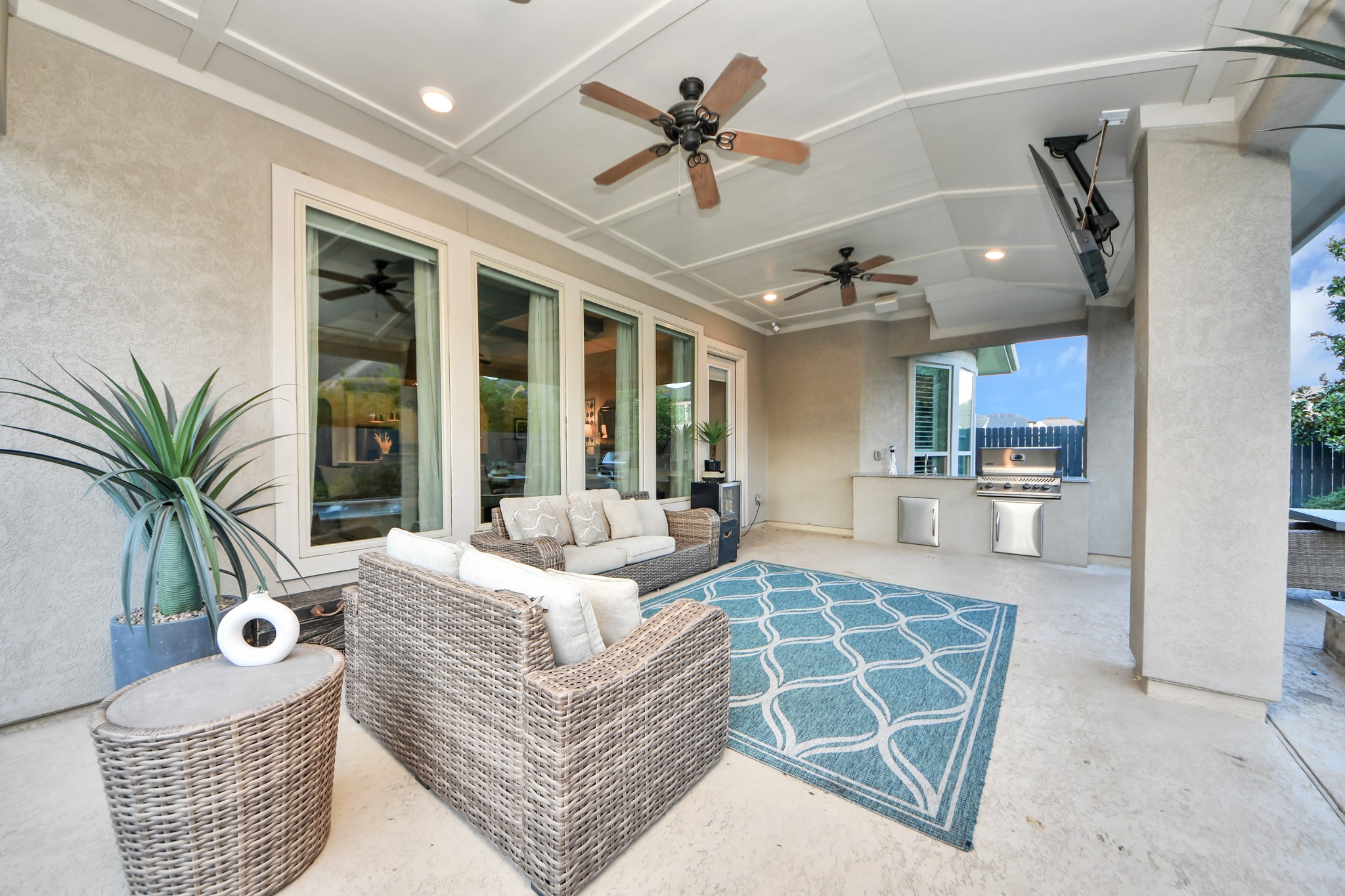 Oversized covered back patio designed for entertaining, featuring a fully equipped outdoor kitchen with built-in gas grill and sink, spacious seating and dining areas, and plenty of room for year-round outdoor gatherings.