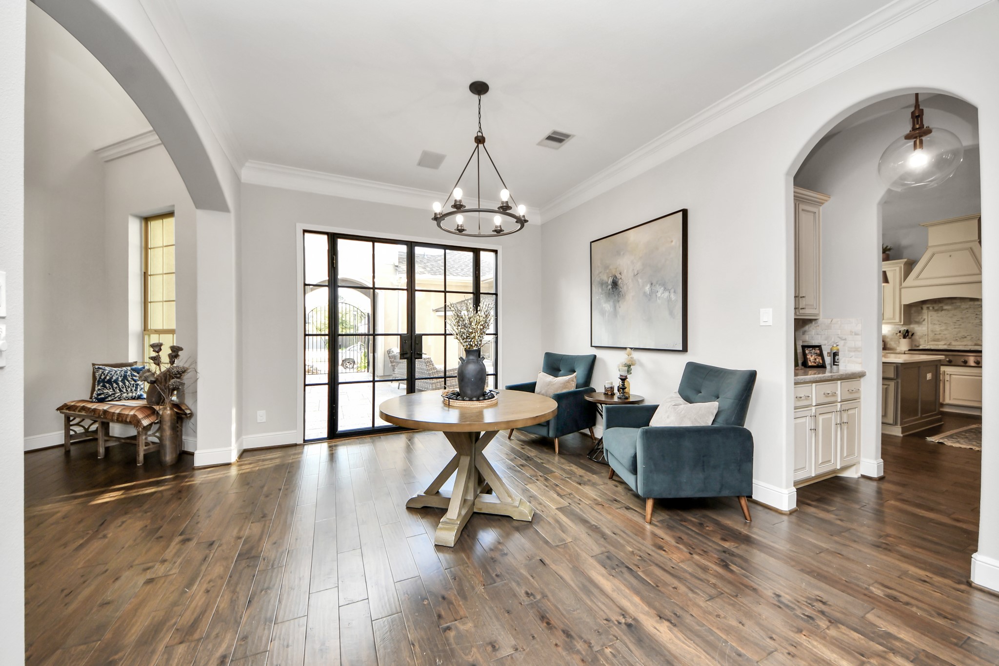 Grand entry foyer featuring elegant arched openings, beautiful hardwood flooring, built-in surround sound speakers, and an open, inviting layout that welcomes you into the home.