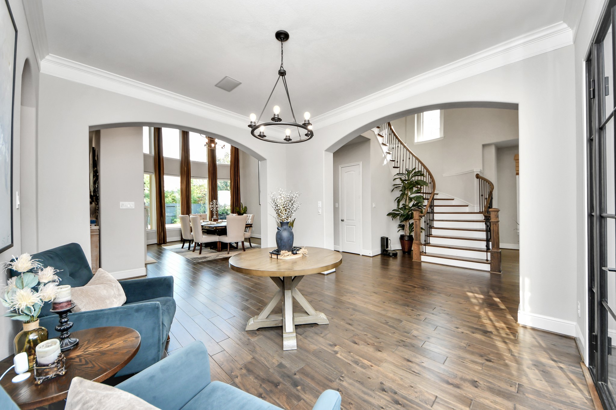 Grand foyer featuring an elegant staircase, graceful arched openings, and a dining room with a wall of windows that fills the space with natural light.