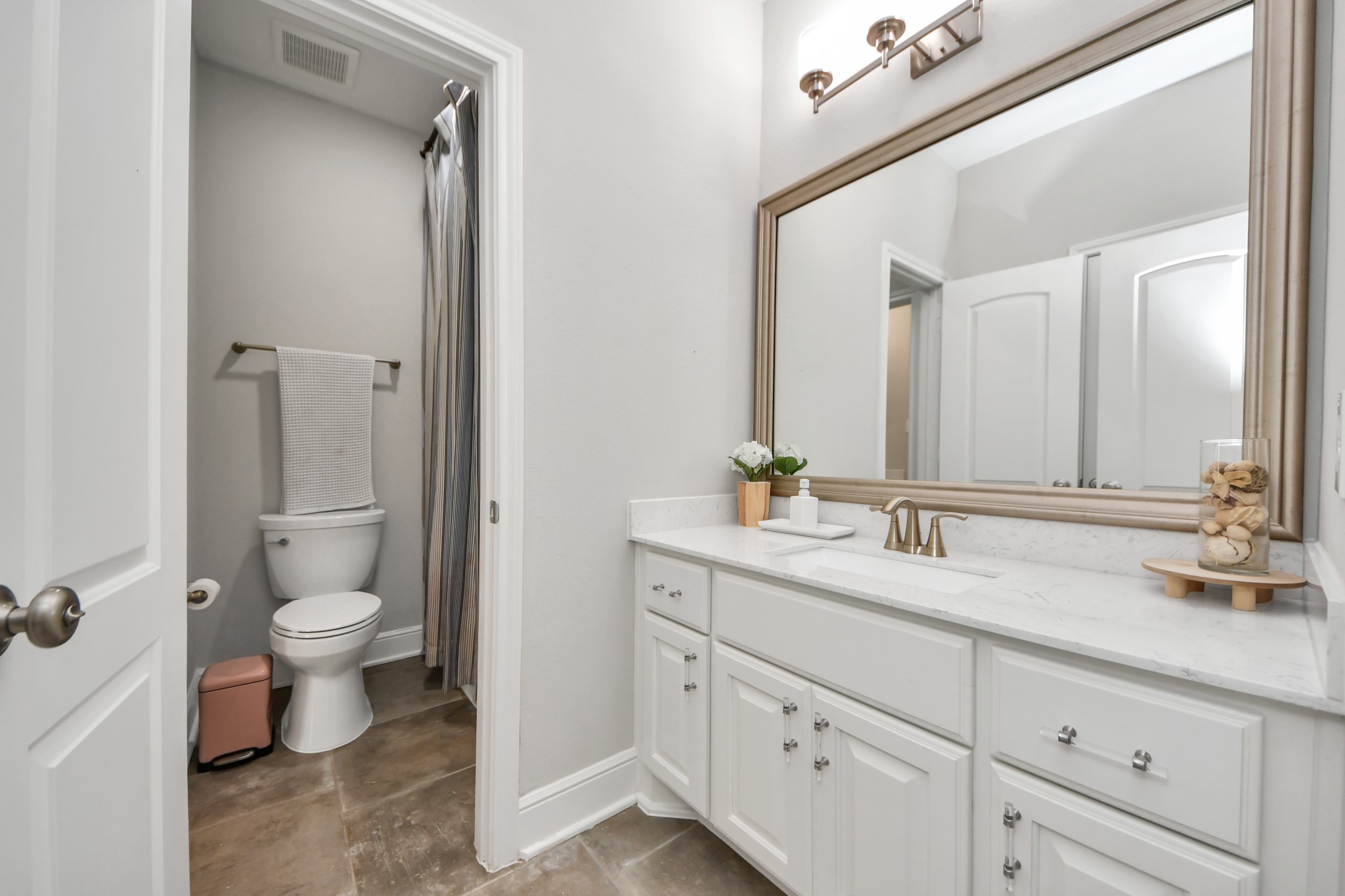 Spacious upstairs bathroom featuring an extended vanity, ample cabinet storage, and convenient hallway access for both secondary bedrooms, the game room, and study.