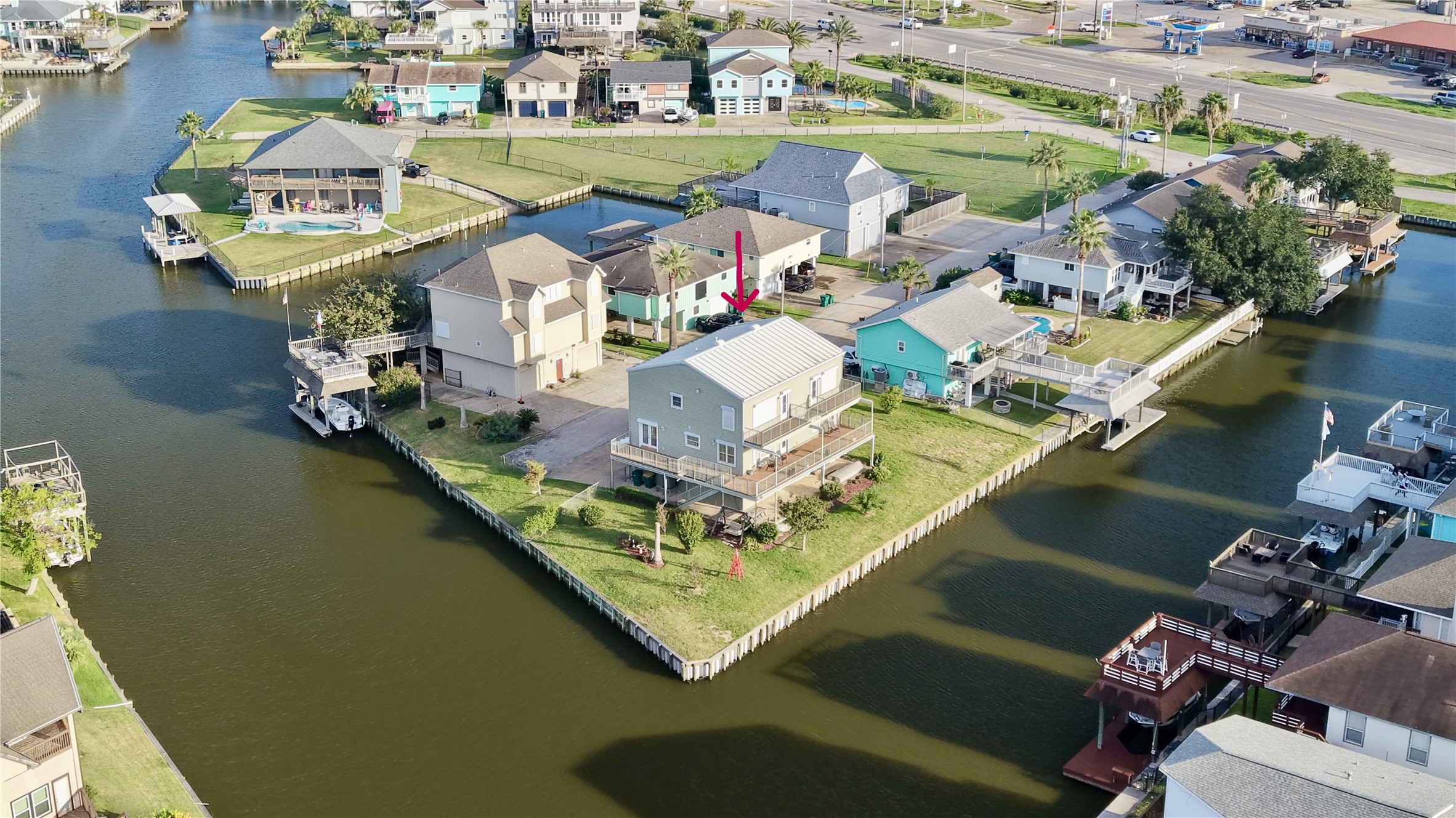 Less wide aerial showing the home's prime point position in Omega Bay, with open canal views, quick water access, and easy reach to shopping and dining just minutes away.