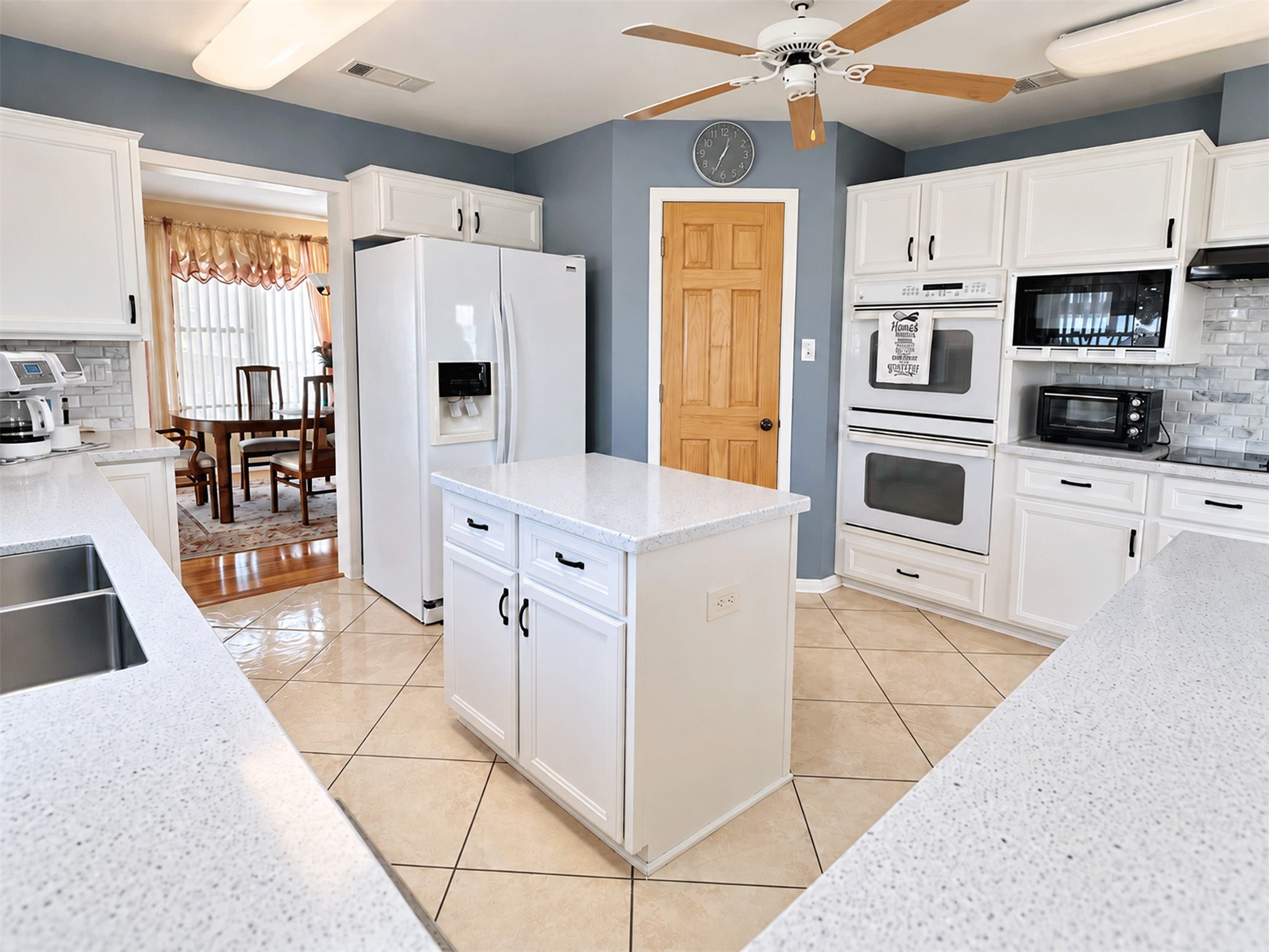 Kitchen features built-in double ovens, a refrigerator nook, and an open flow to the dining room.