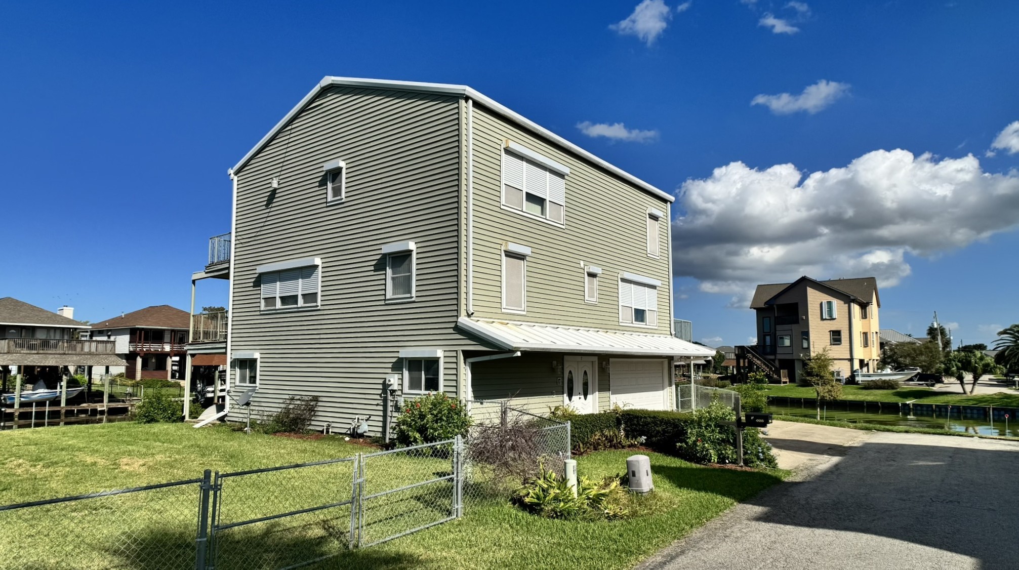 Welcome to 7 S Skimmer Street, a three-story waterfront home in Omega Bay with a wide driveway and oversized garage (enclosed ground level).