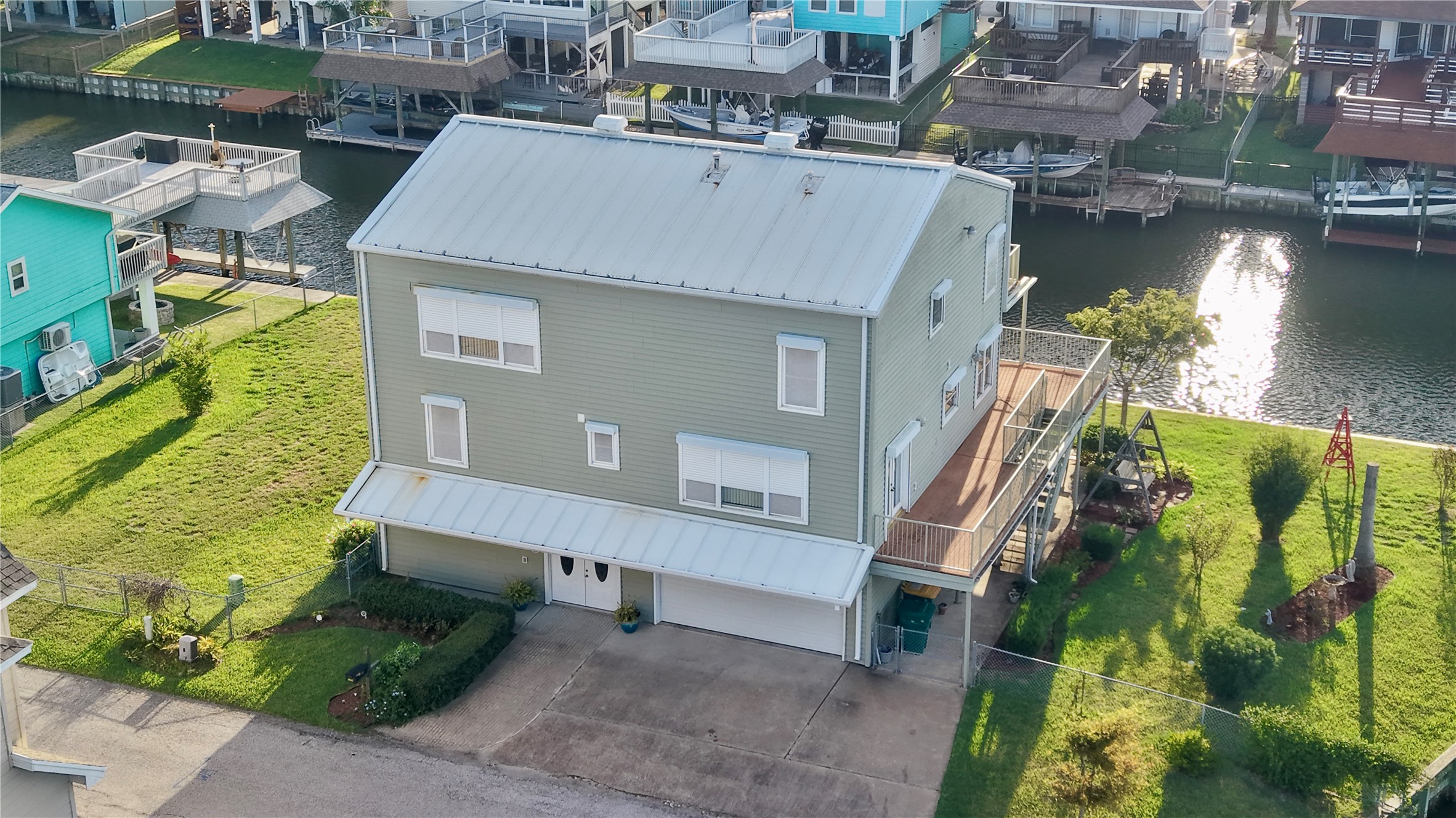 Aerial view of 7 S Skimmer Street: a 1996 custom steel-frame home on two lots, with a metal roof, a spacious yard, and a new vinyl bulkhead wrapping the waterfront.
