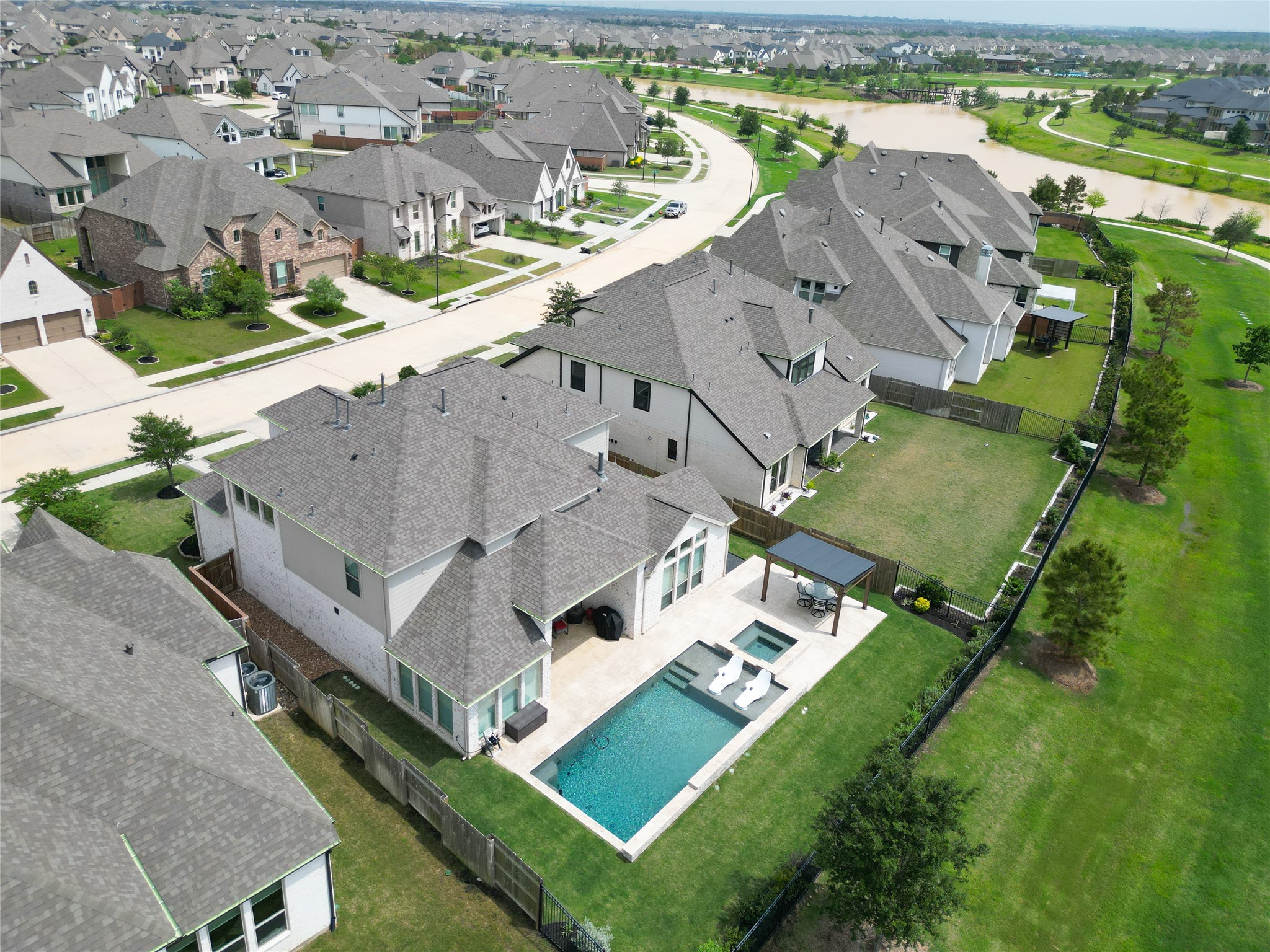 A modern suburban neighborhood with spacious homes. The featured property includes a backyard with a swimming pool, spa, and a covered patio area, set in a well-maintained yard. The neighborhood is characterized by neatly lined houses, green spaces, and nearby water features, offering a serene and inviting environment. A modern suburban neighborhood with spacious homes. The featured property includes a backyard with a swimming pool, spa, and a covered patio area, set in a well-maintained yard. The neighborhood is characterized by neatly lined houses, green spaces, and nearby water features, offering a serene and inviting environment.