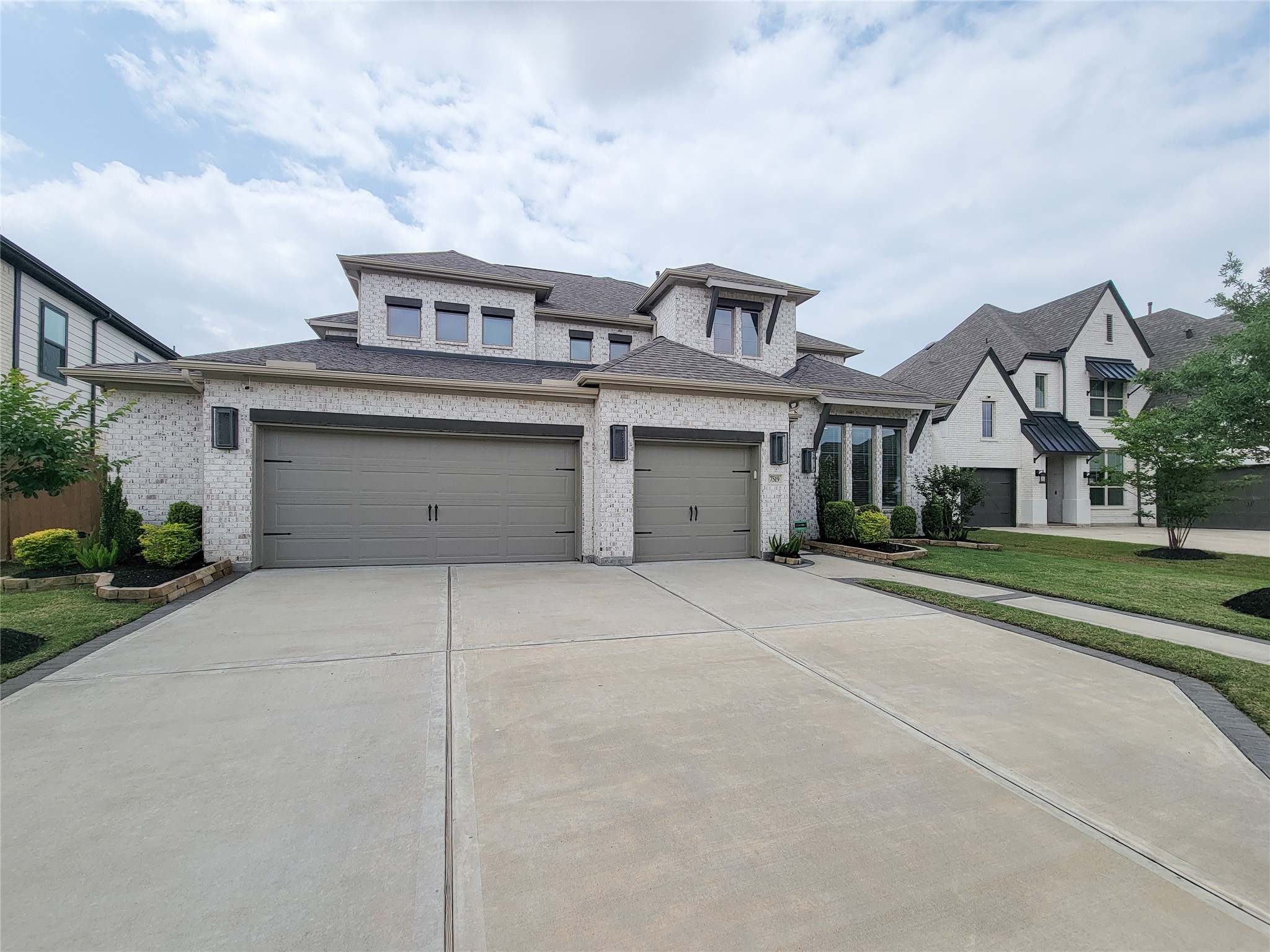 This is a modern two-story brick home with a three-car garage and well-maintained landscaping. The facade features large windows and a spacious driveway in a suburban neighborhood. This is a modern two-story brick home with a three-car garage and well-maintained landscaping. The facade features large windows and a spacious driveway in a suburban neighborhood.