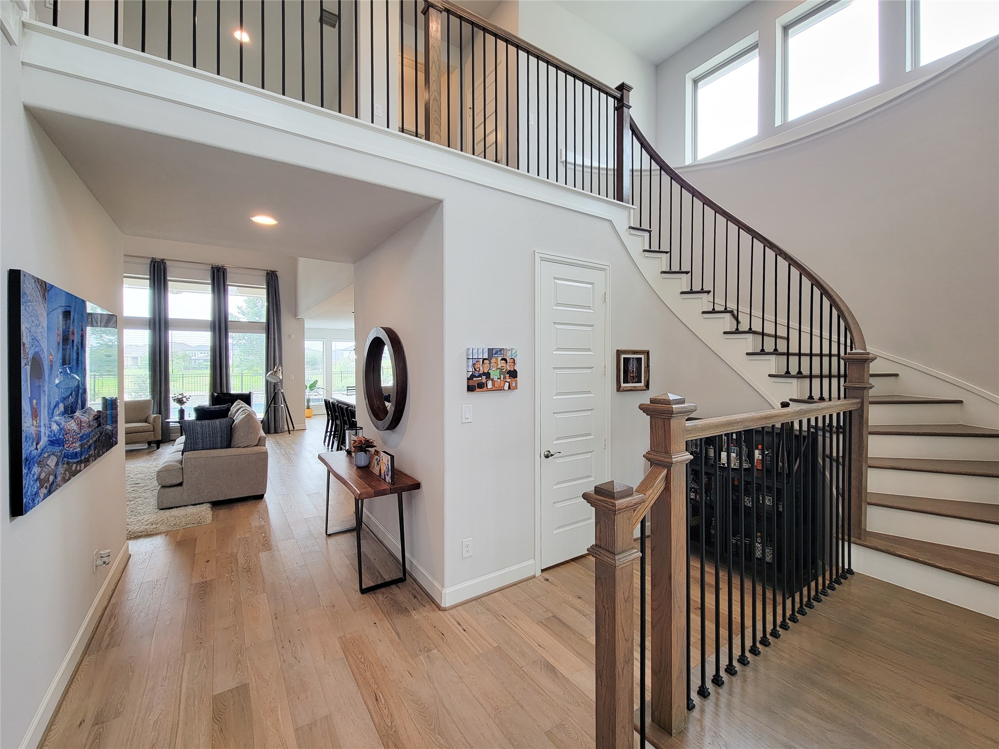 Bright, open entryway with a stunning curved staircase and modern railing. The space features light wood flooring and high ceilings, leading to a spacious living area with large windows and natural light. Bright, open entryway with a stunning curved staircase and modern railing. The space features light wood flooring and high ceilings, leading to a spacious living area with large windows and natural light.