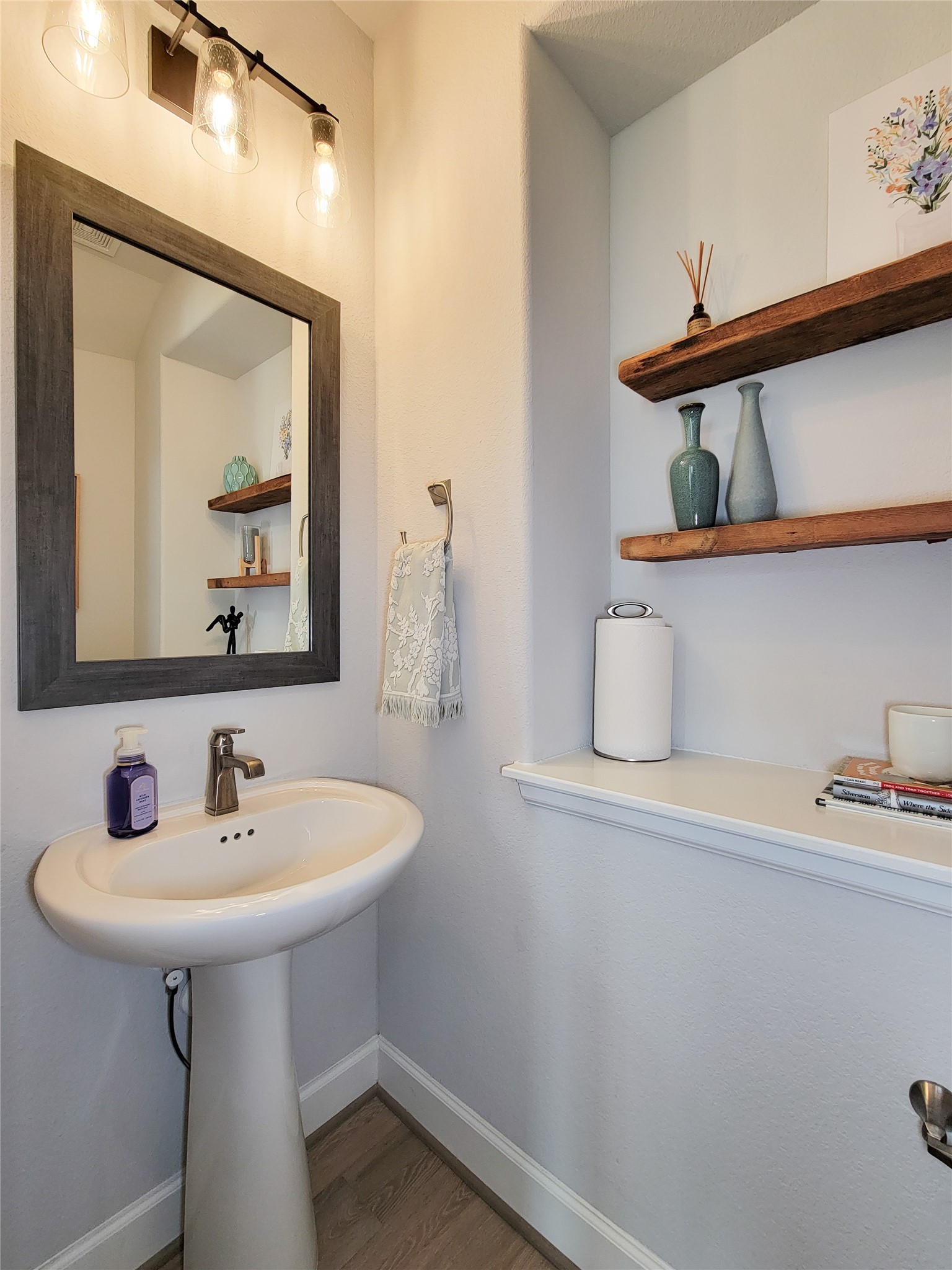Half bathroom featuring a pedestal sink with a modern faucet and a stylish mirror.