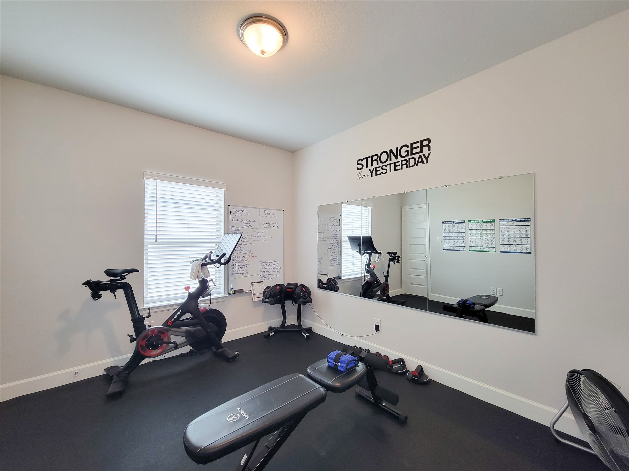 This bedroom is being used as a home gym. The room is bright and motivational, featuring exercise charts and an inspirational quote on the wall. Can be used as bedroom.
