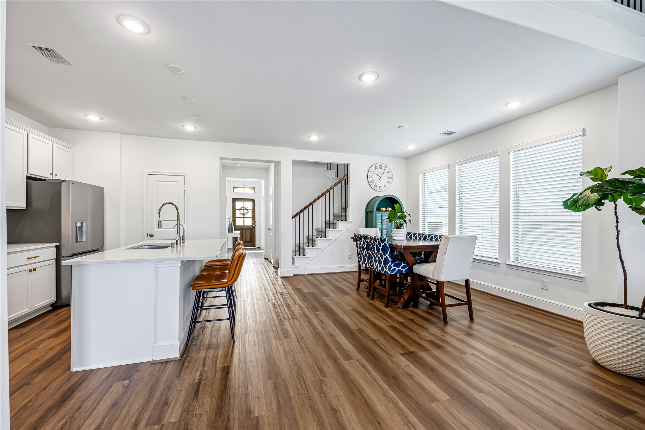 A spacious casual dining area sits beside the island kitchen, with generous windows and upgraded flooring extending throughout the space.