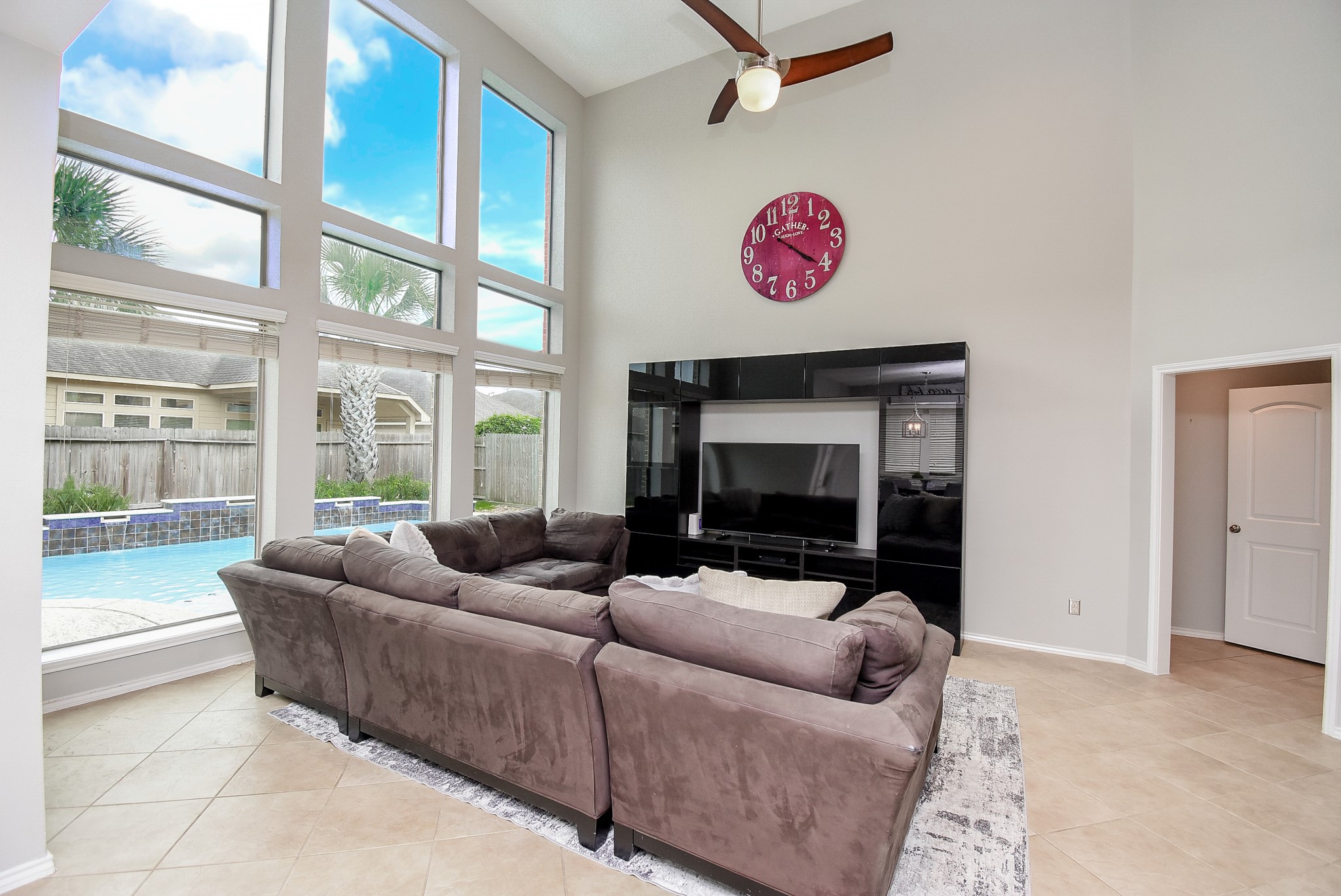 The living room features a wall of windows to enjoy views of the backyard oasis!