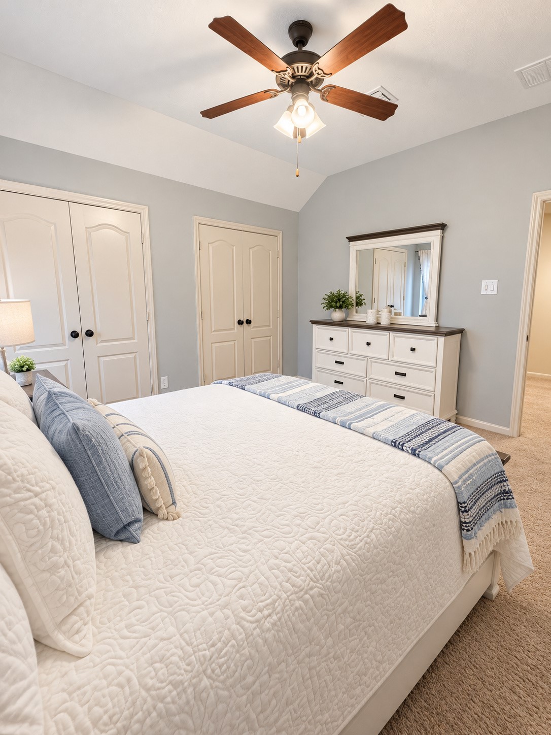 Comfortable secondary bedroom with vaulted ceiling, soft carpeting, and ample natural light.