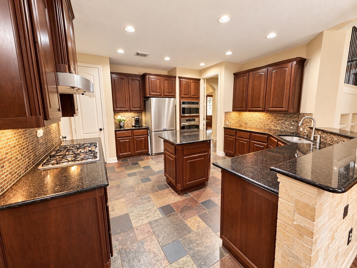 Beautifully appointed kitchen with extensive cabinetry, tile backsplash, and generous counter space.