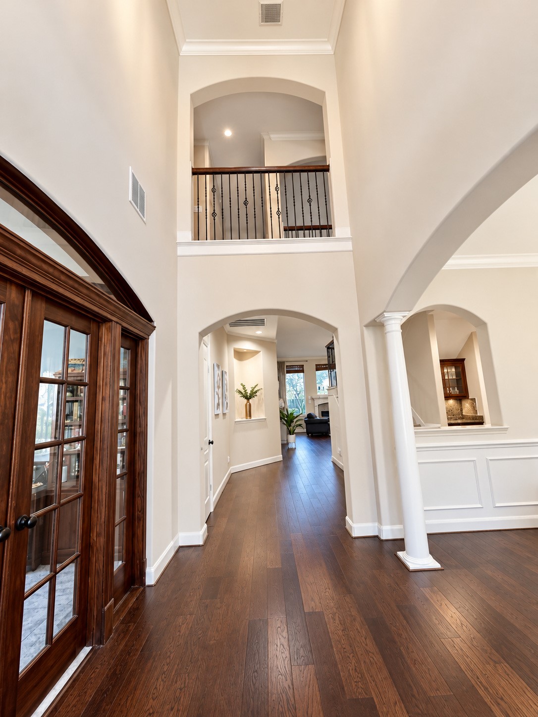 Impressive two-story entryway featuring soaring ceilings, graceful archways, and rich wood flooring.