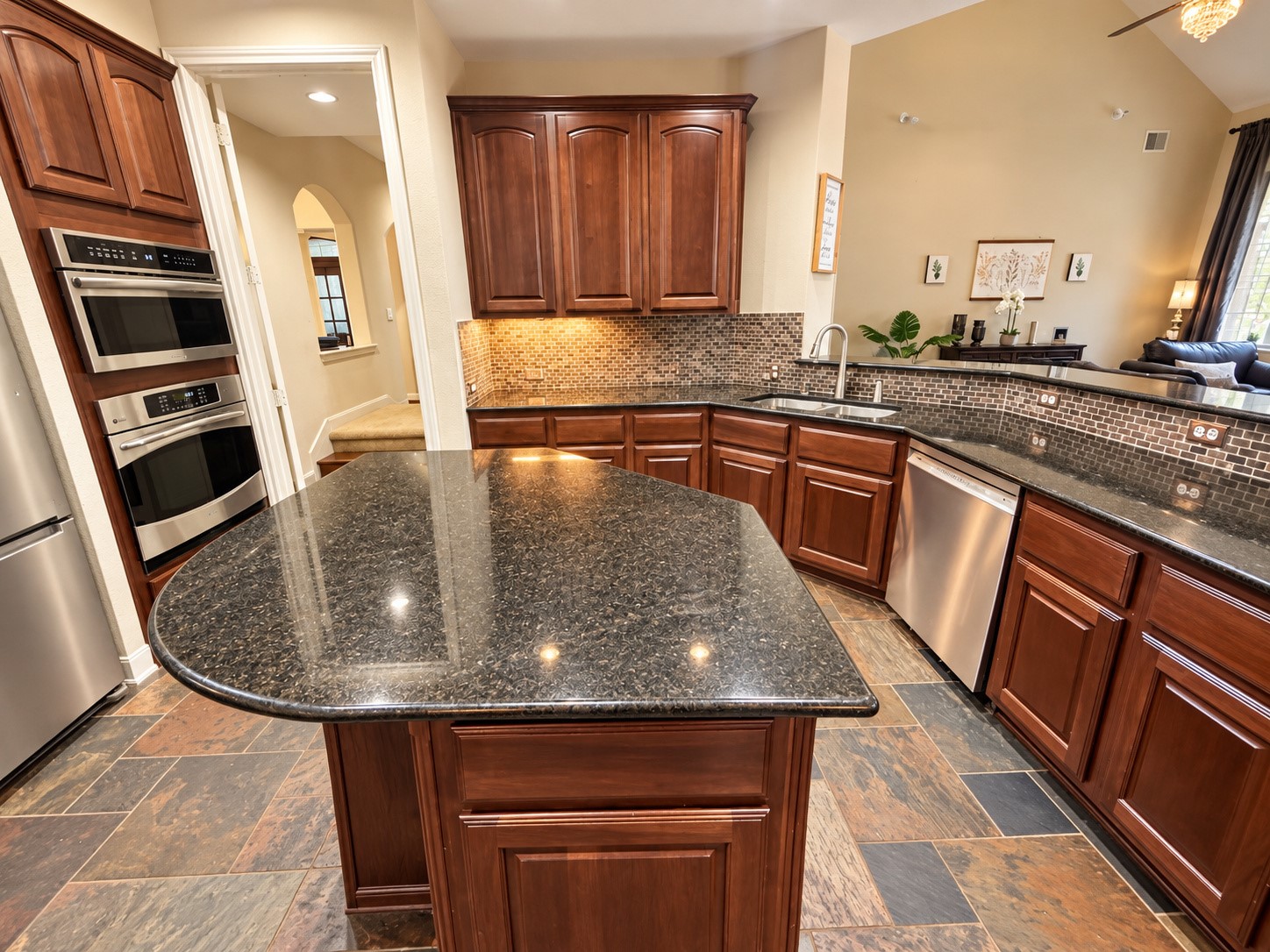Spacious kitchen featuring rich wood cabinetry, dark countertops, stainless steel appliances, and a center island.
