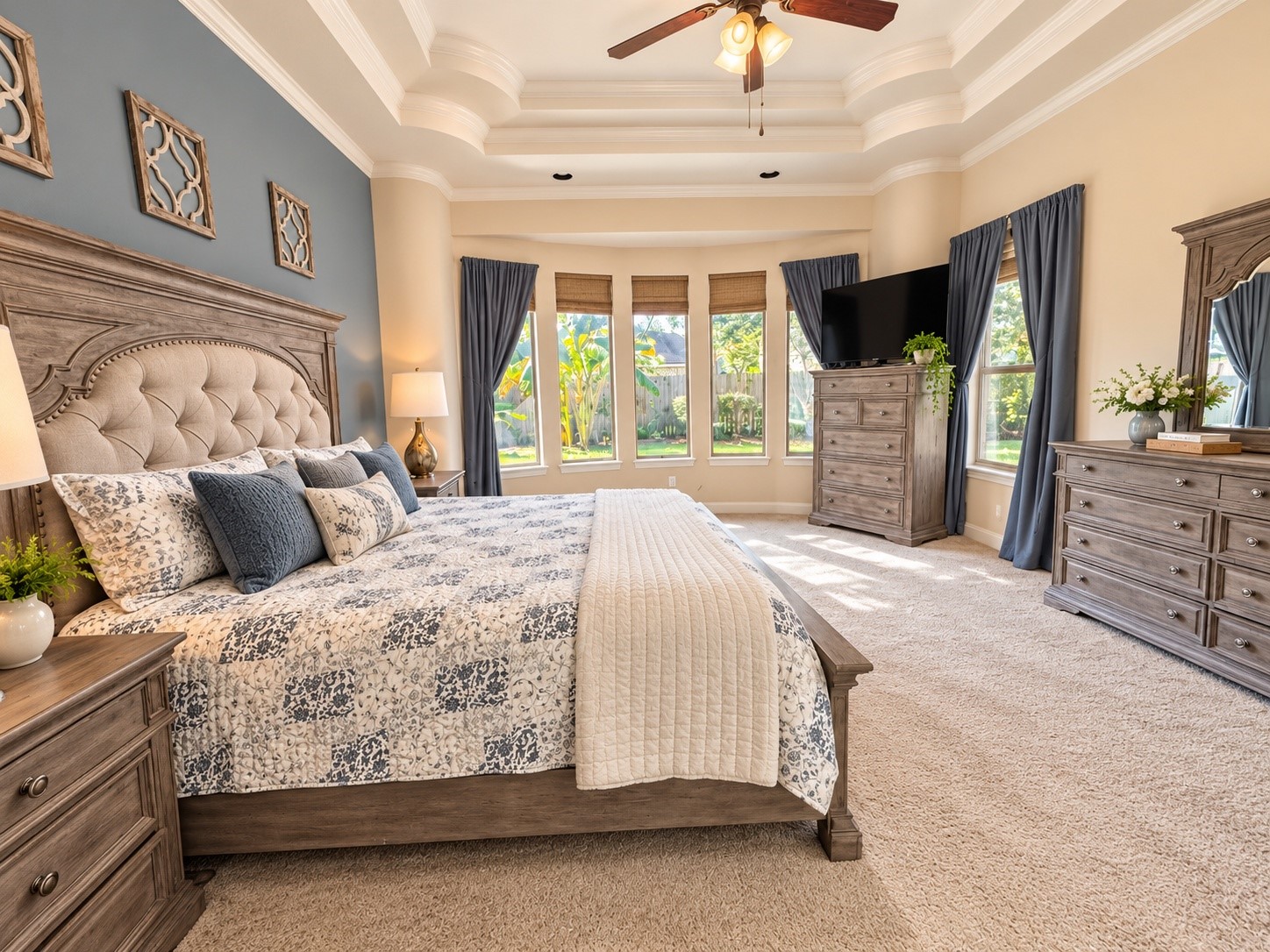Relaxing primary bedroom with a decorative accent wall, generous floor space, and attractive ceiling details.