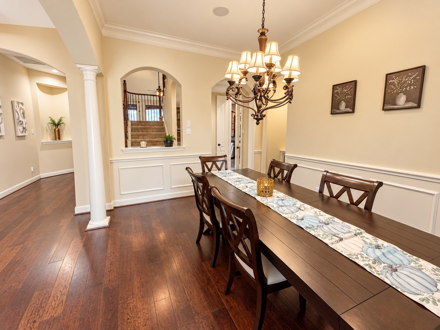 Warm and inviting formal dining room featuring rich wood floors, elegant molding, and a beautiful chandelierperfect for sharing meals and making memories.