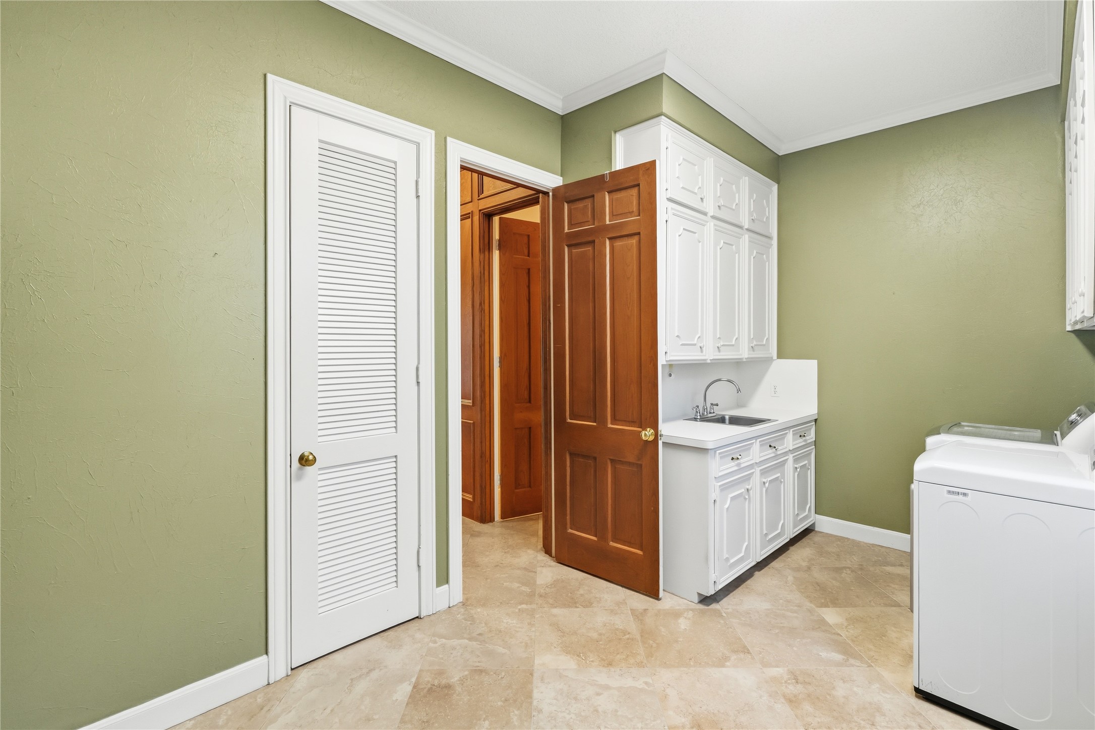 Laundry room with cabinetry, a convenient sink, and washer-dryer setup.