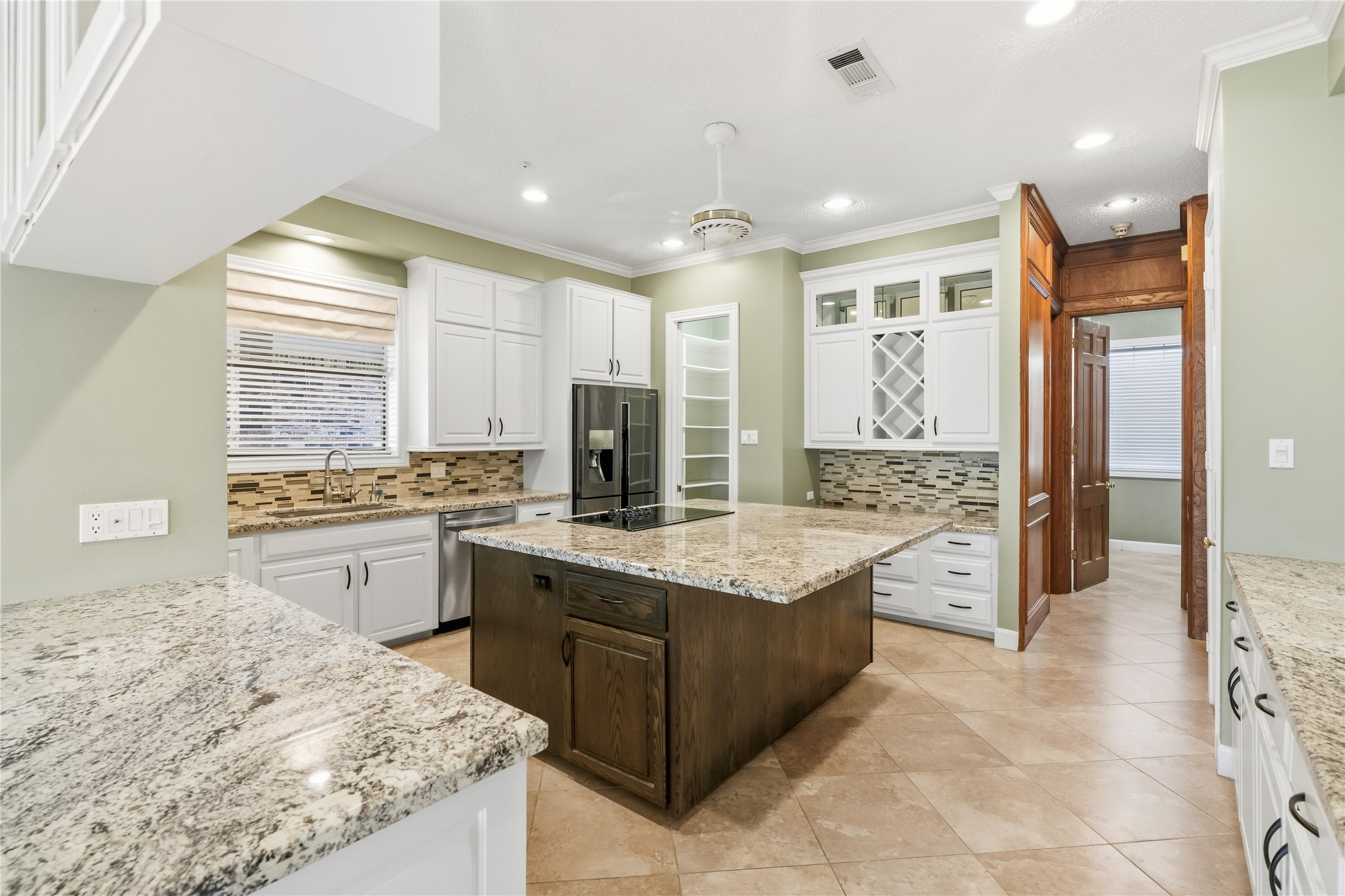 Spacious kitchen featuring sleek granite countertops, a center island, and ample cabinetry with stylish glass fronts.