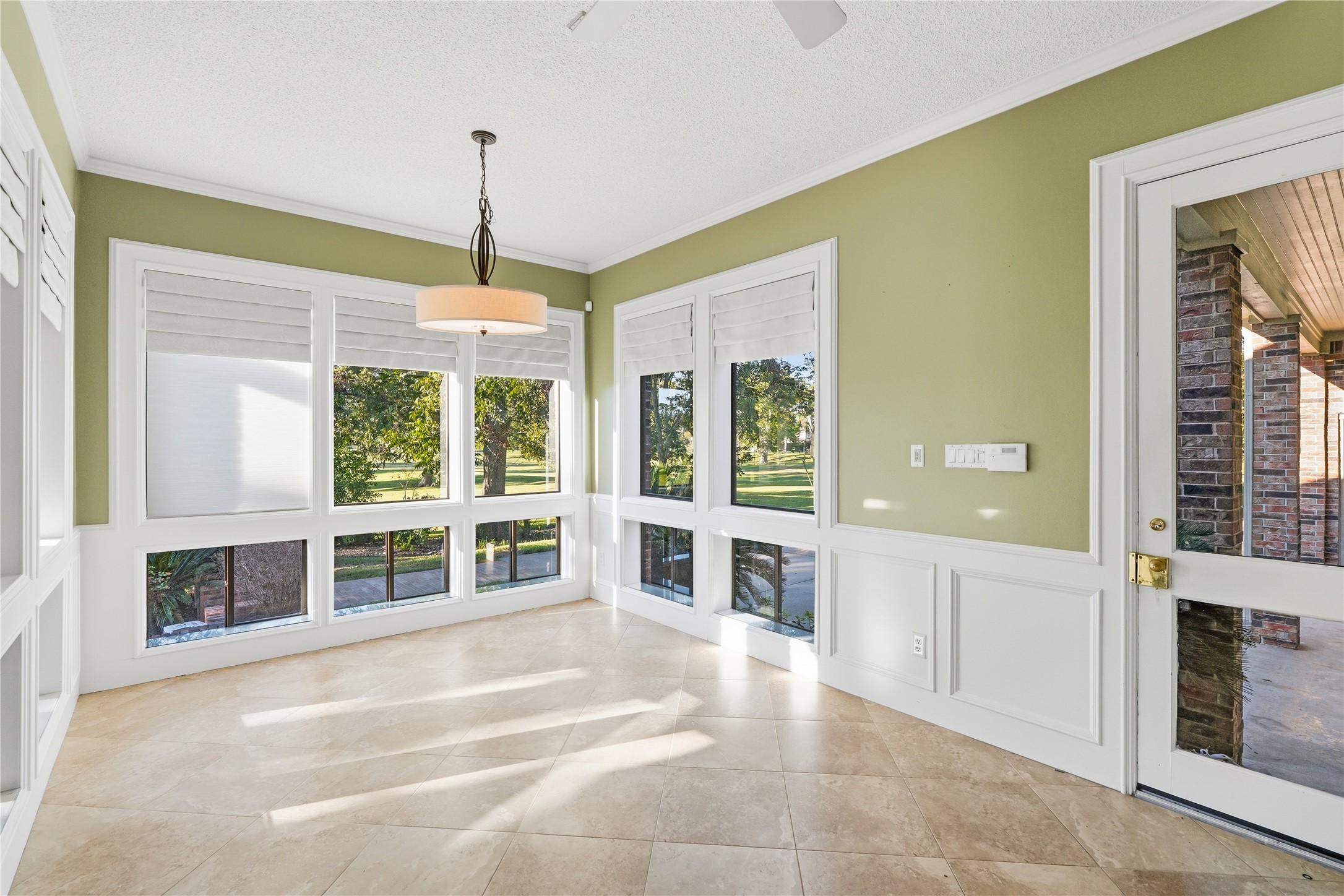 Bright and inviting breakfast room with large windows, elegant tile flooring, and a stylish light fixture, perfect for enjoying the scenic outdoor views.