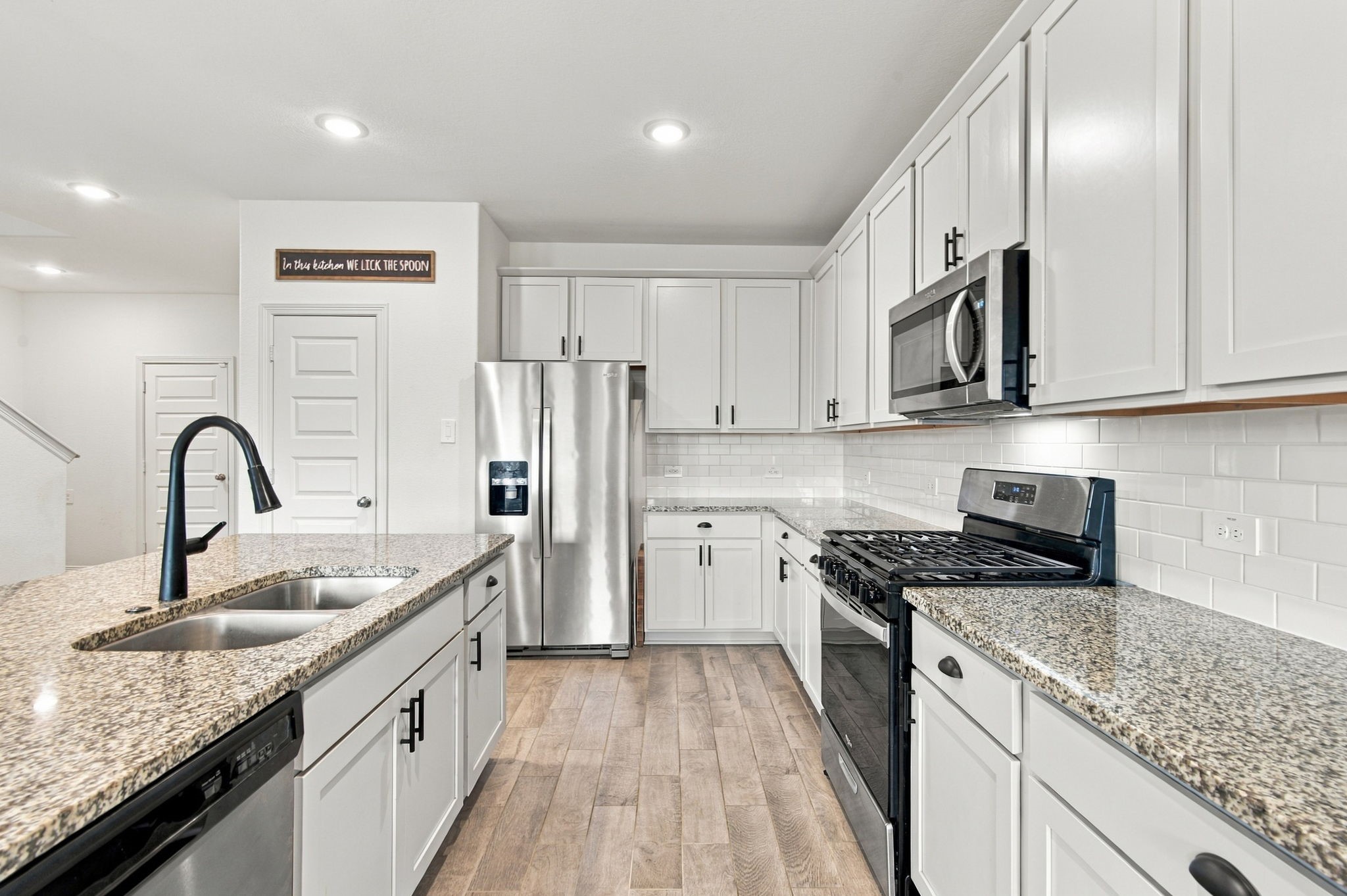 Abundant upper and lower cabinetry provides excellent storage, while recessed ceiling lighting and durable wood-look tile flooring complete this inviting space, perfect for everyday cooking and entertaining.