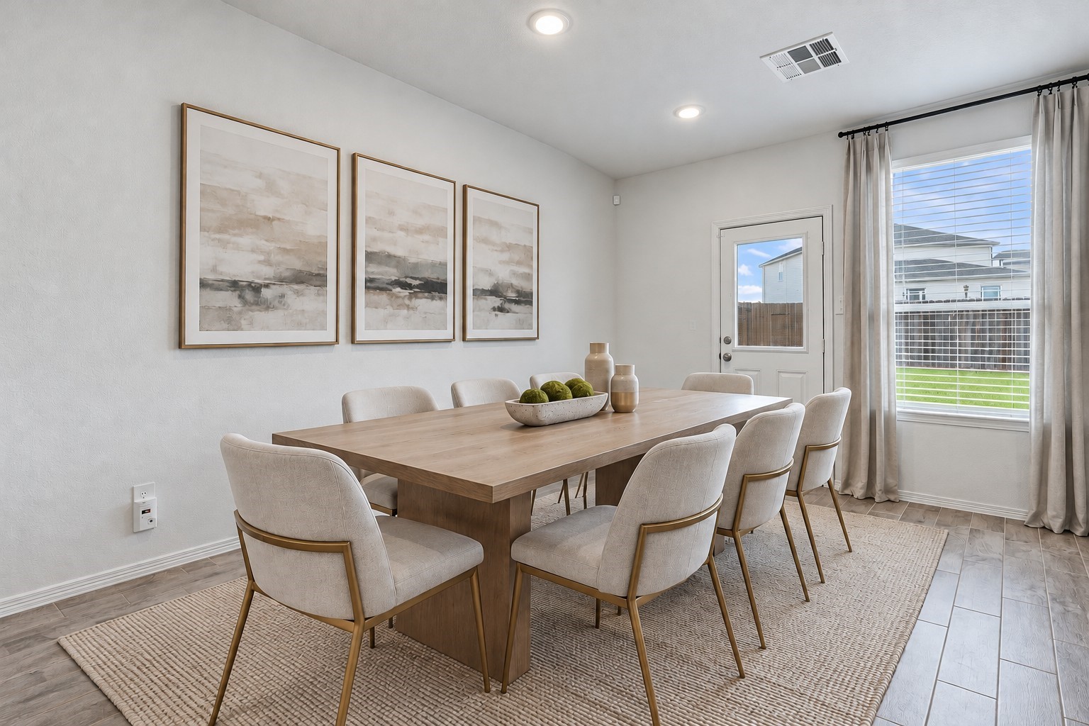 Virtually Staged: This bright and spacious dining area features a clean, modern design with neutral wall tones, beautiful wood-look tile flooring, and recessed ceiling lighting. A large window welcomes abundant natural light and offers views of the backyard, while a convenient exterior door provides direct access to the outdoor space.