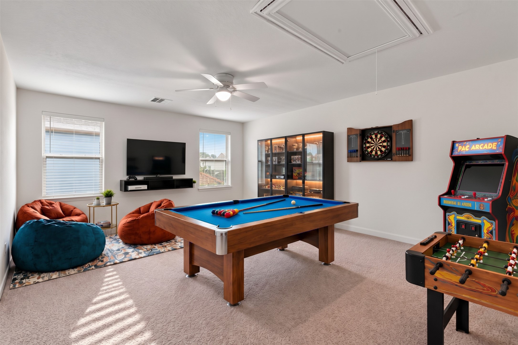 Virtually Staged: This expansive upstairs room offers a bright, open layout with endless possibilities for entertainment, recreation, or additional living space. Two generously sized windows with white blinds welcome abundant natural light, creating an airy and inviting atmosphere. A ceiling fan with integrated lighting enhances everyday comfort, while convenient attic access provides added functionality.