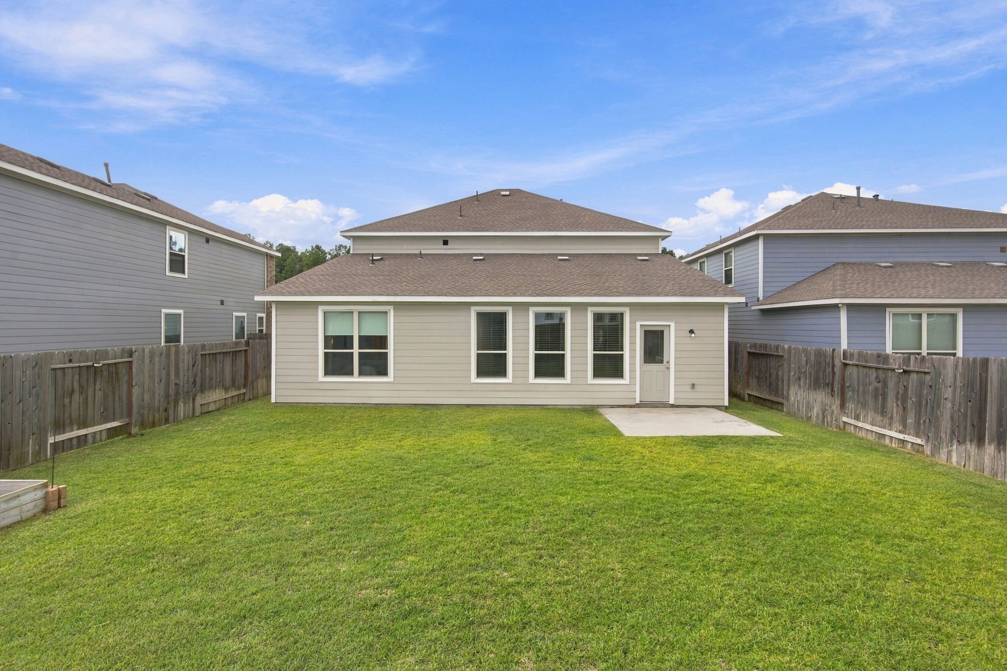 This spacious backyard offers a wide-open green lawn surrounded by a wooden privacy fence, creating an inviting outdoor space with plenty of room for recreation, relaxation, and entertaining.